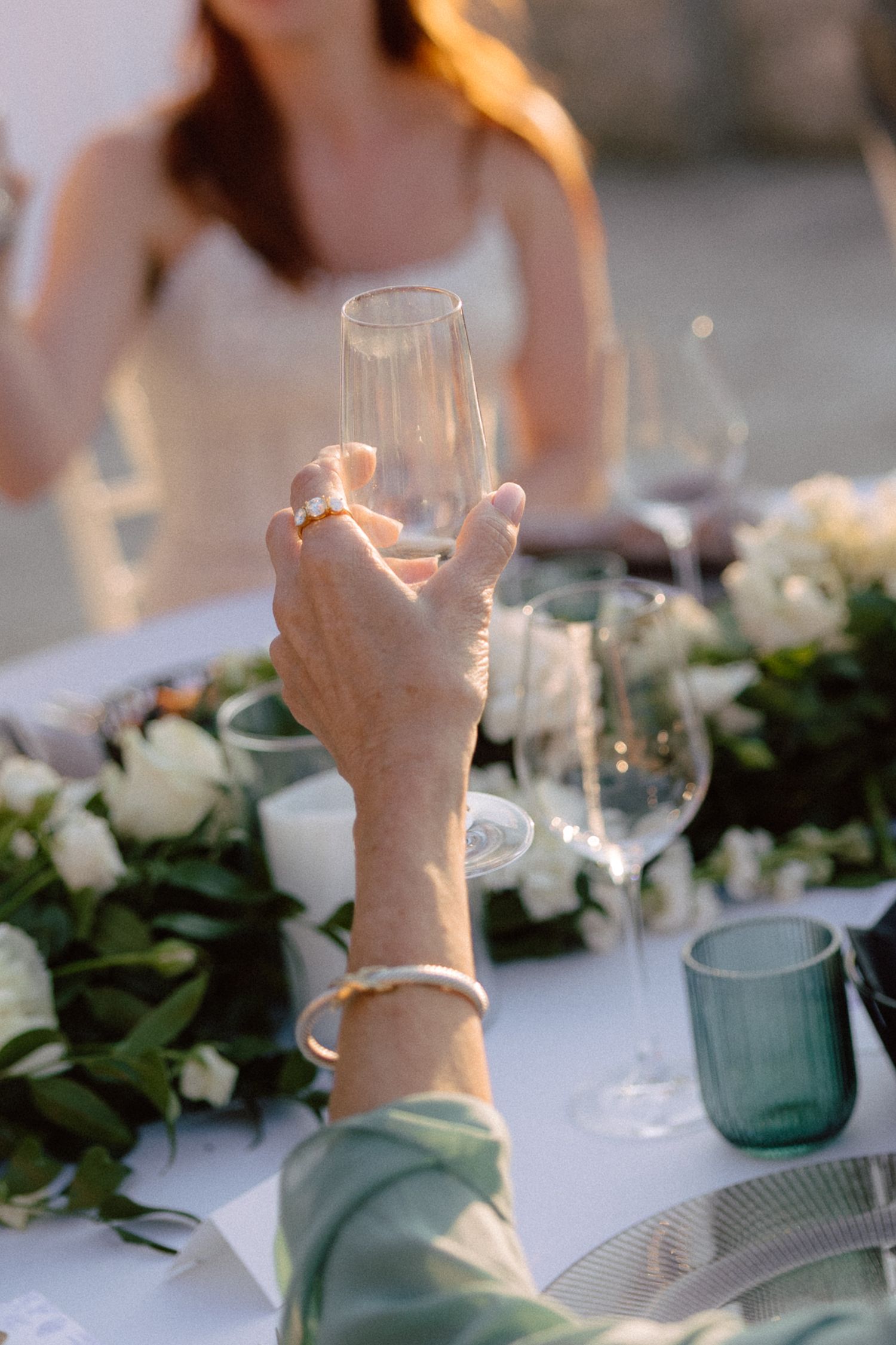 Elegant table setting at an outdoor wedding with white linens and green foliage garlands.