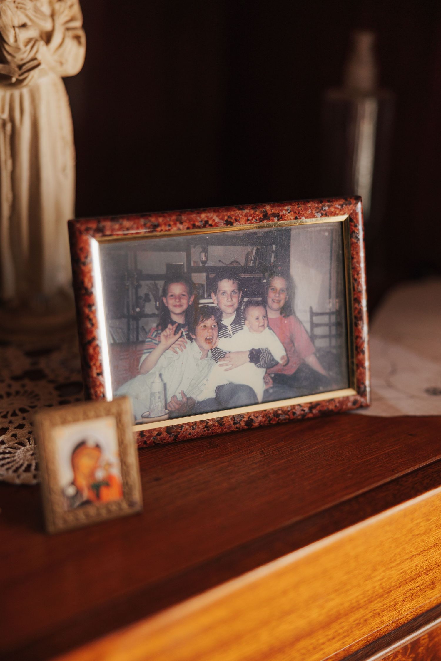 Framed family photographs displayed on a wooden surface in warm lighting.