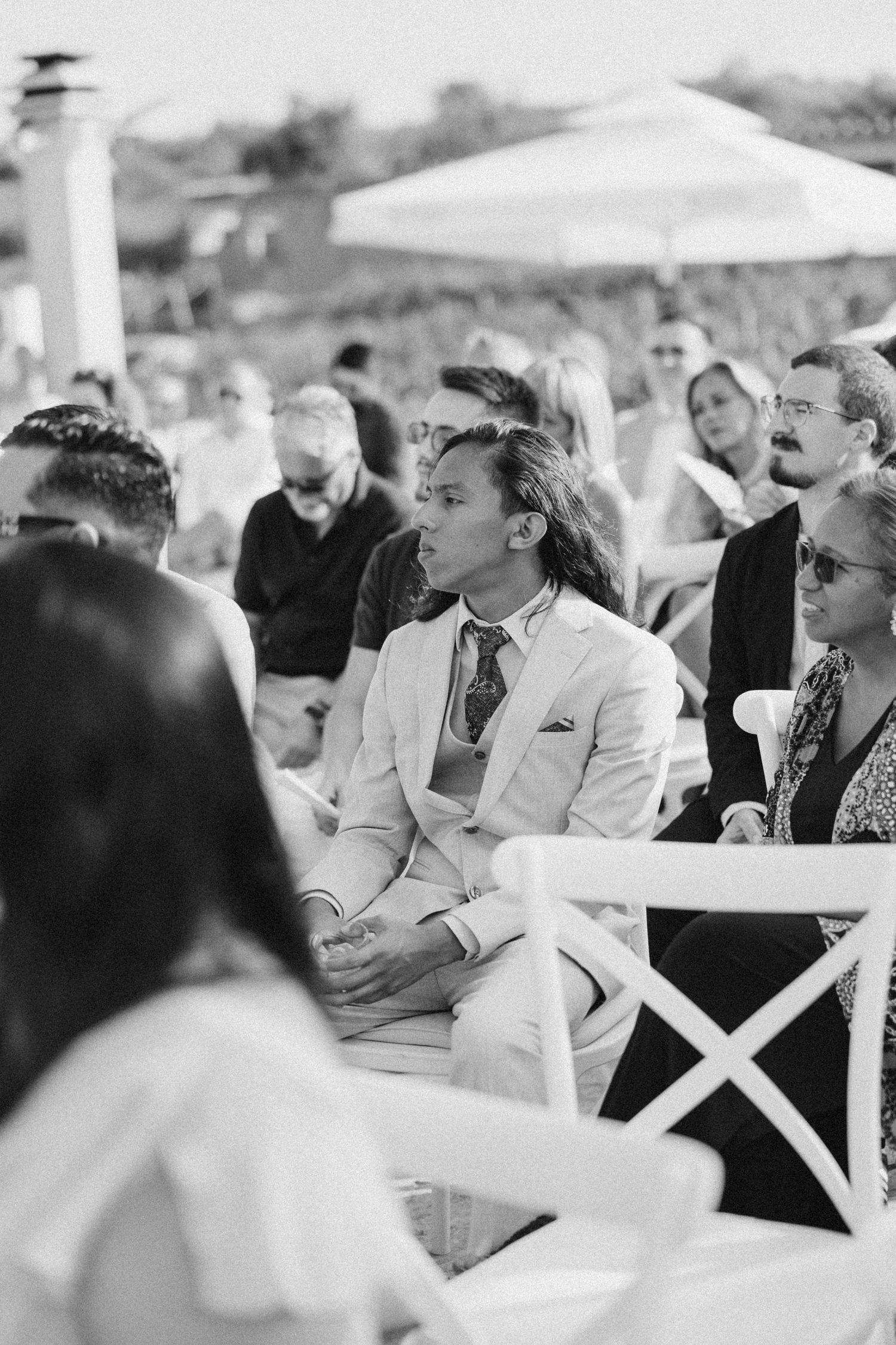 Black and white photo of wedding guests seated in rows watching the ceremony.