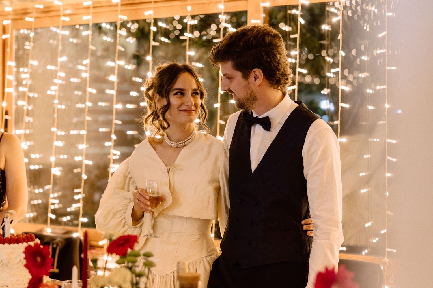 A couple shares an intimate moment at their reception under string lights.