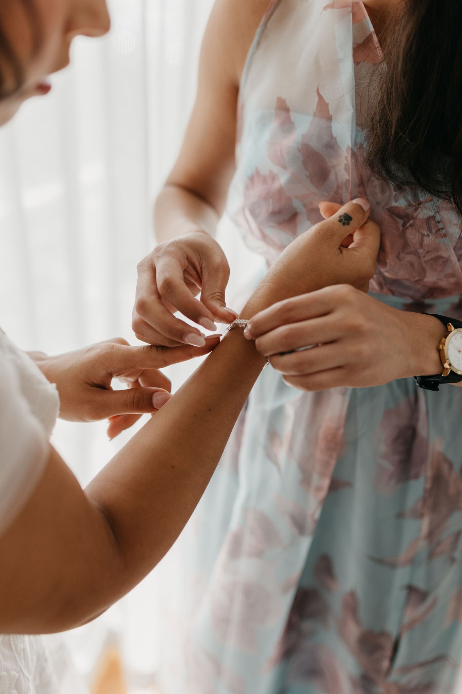 Close-up of hands fastening jewelry during wedding preparations.