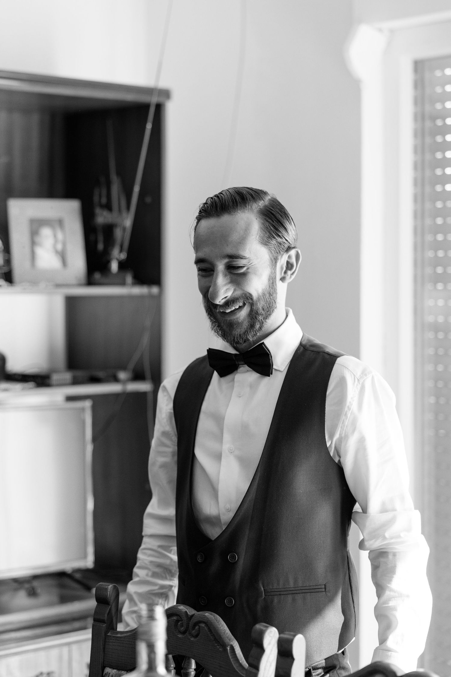 Elegant black and white portrait of groom in formal attire smiling.