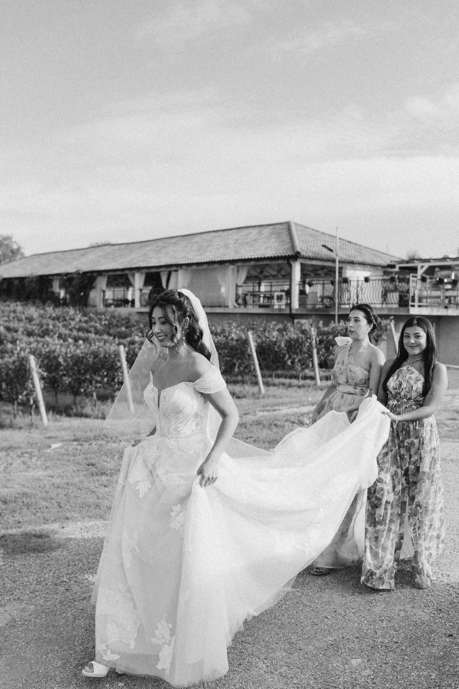 Wedding party helping with dress in black and white outdoor photography.