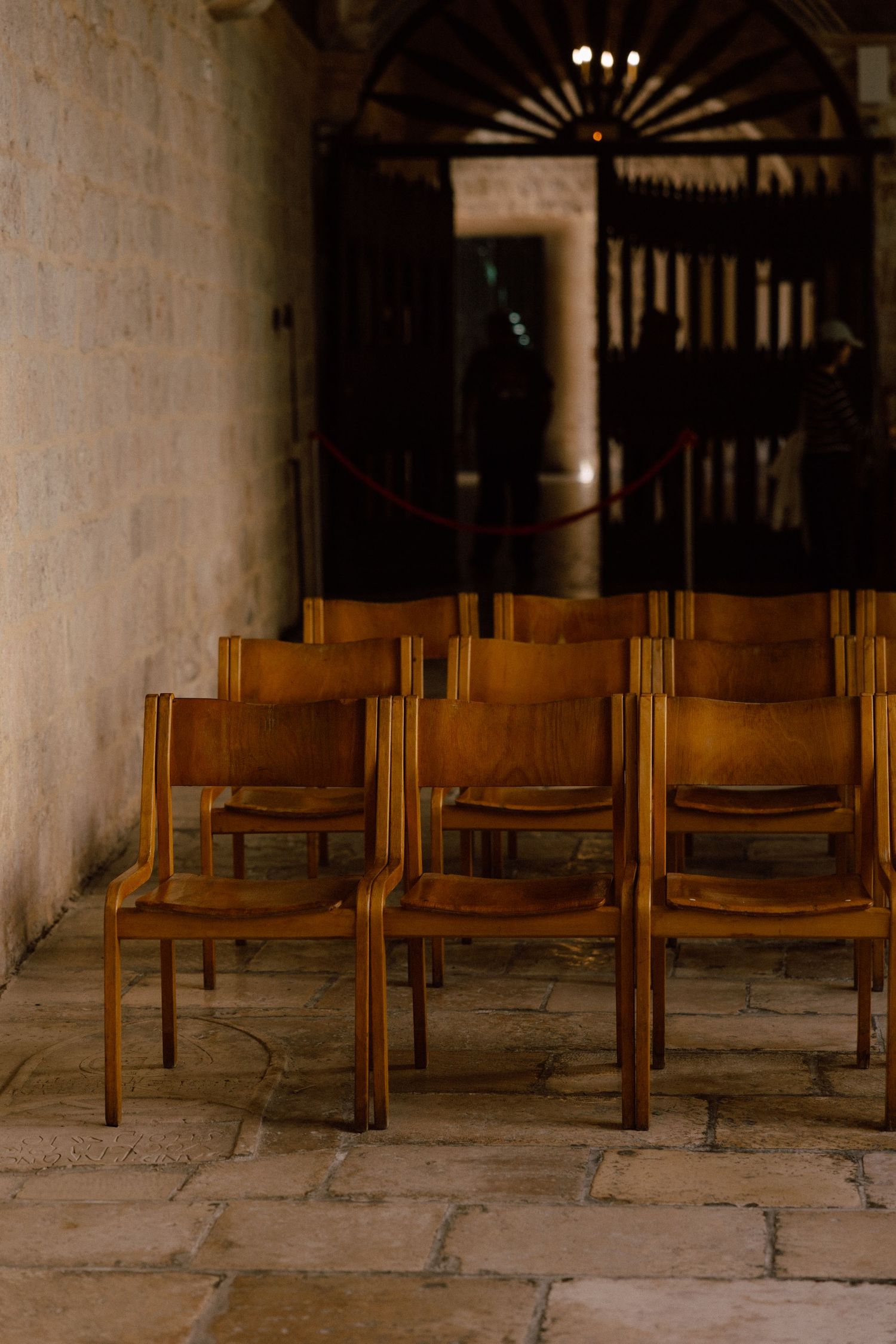Row of wooden chairs arranged along a stone floor in a historic building interior  in Dubrovnik, Croatia.