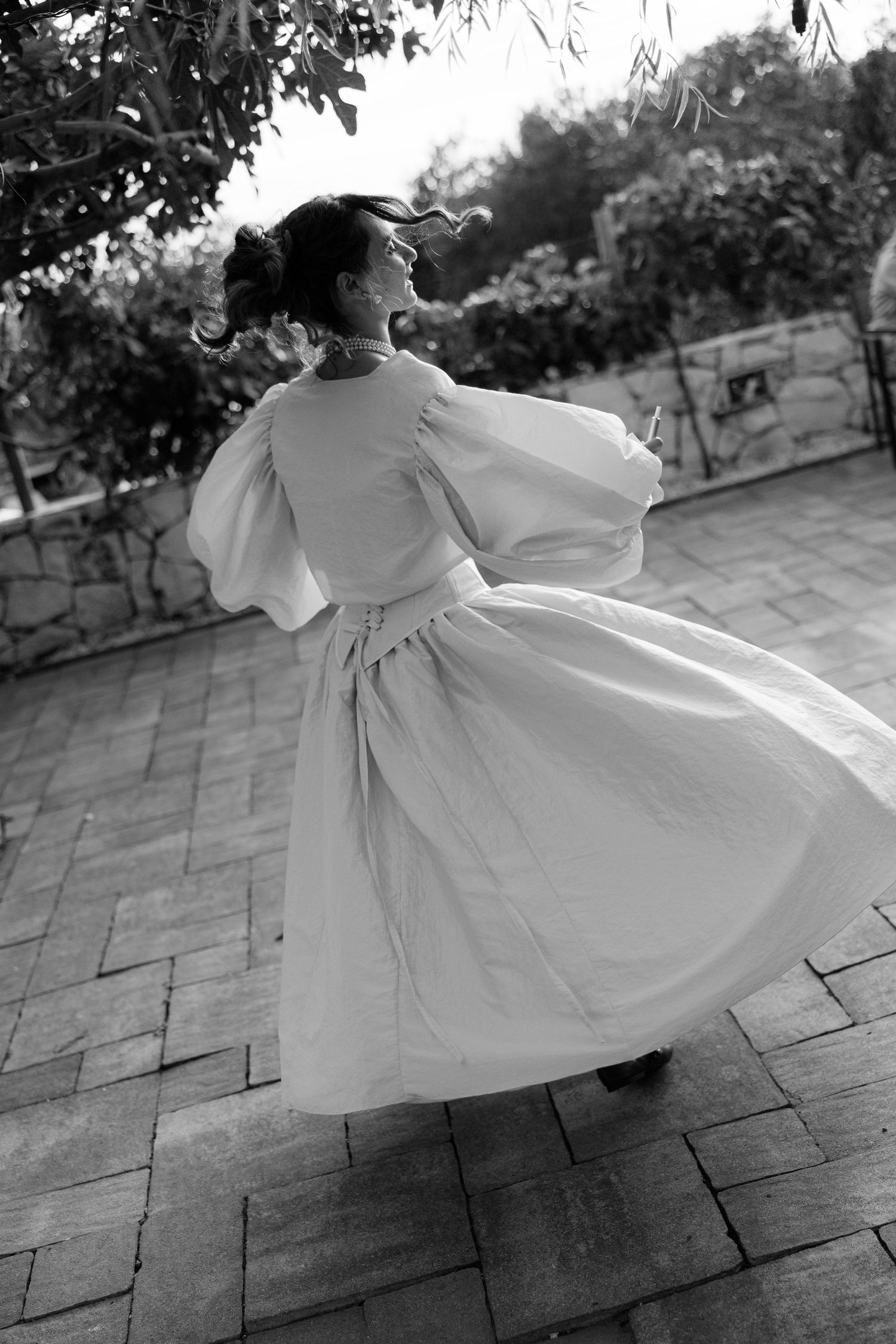 Ethereal black and white photo sequence of bride twirling in flowing white dress on stone patio.