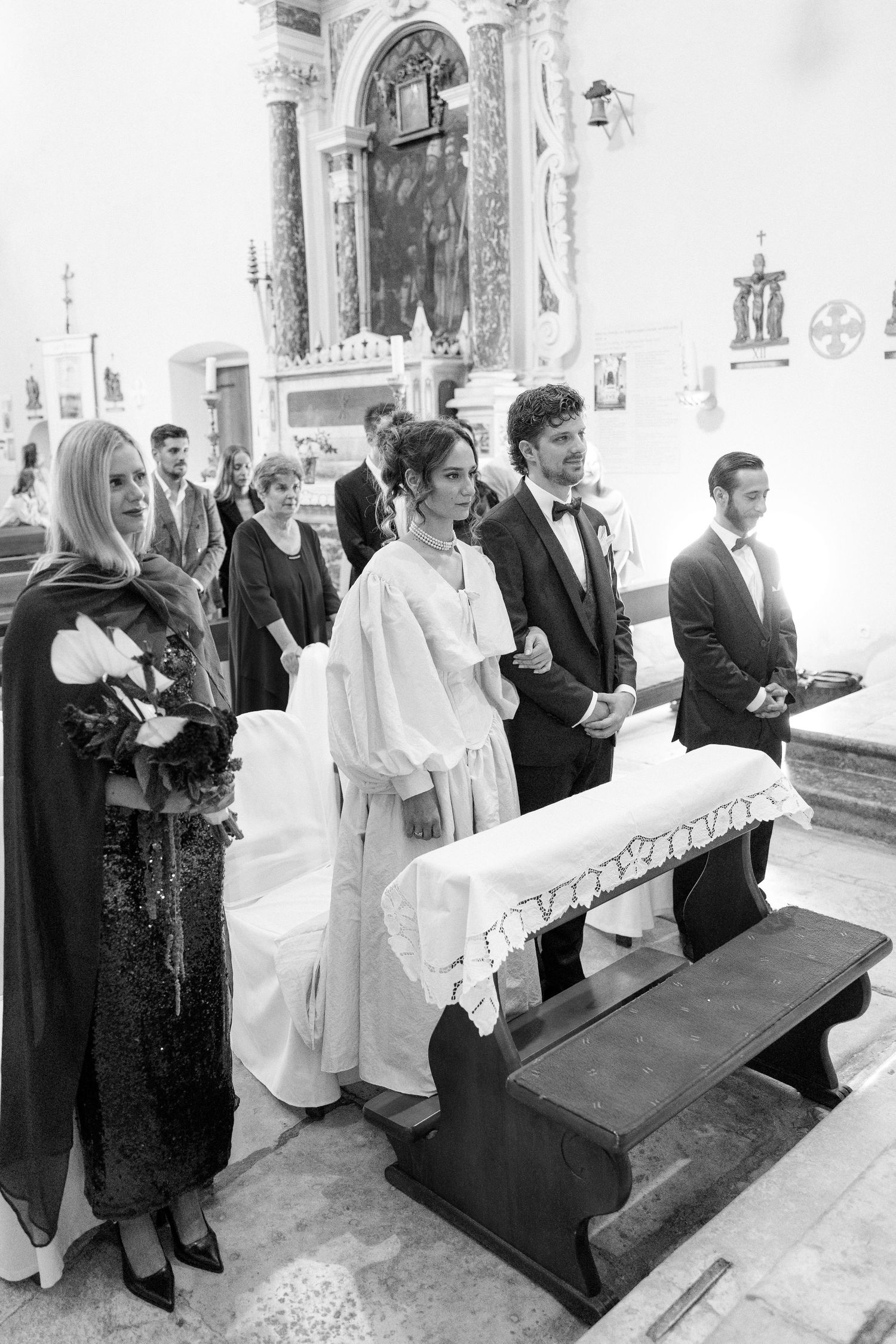 A traditional church wedding ceremony with guests standing in front of an ornate altar.