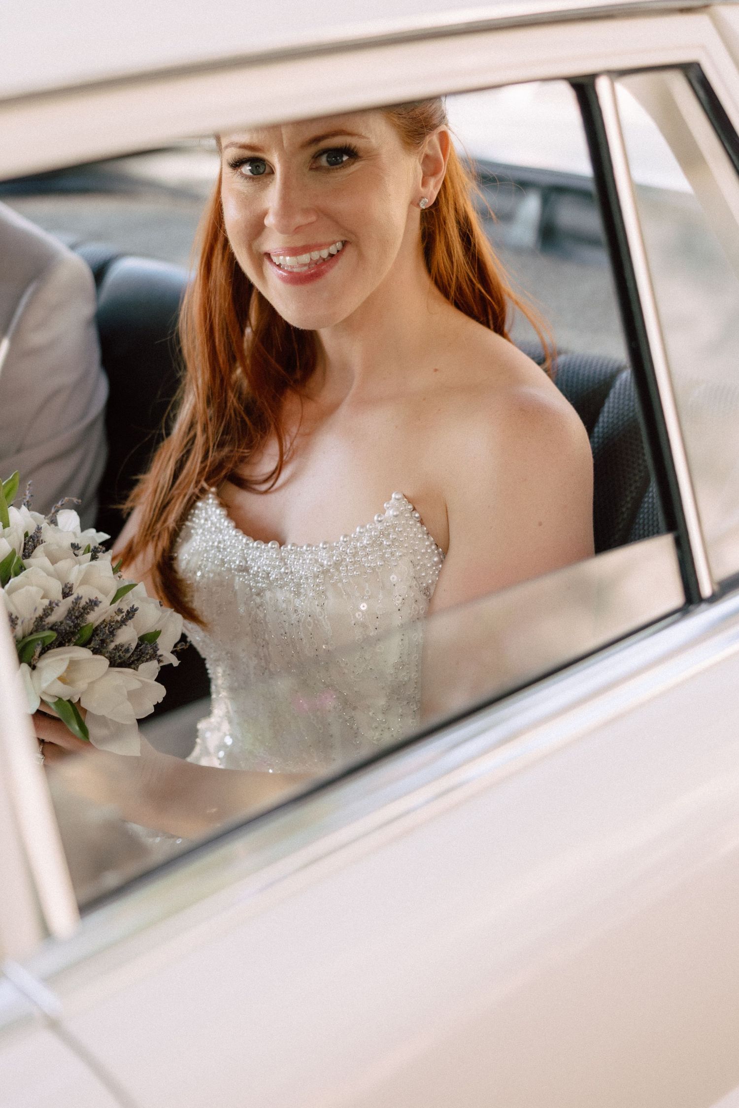 View through classic car window showing sparkly white bridal gown details.