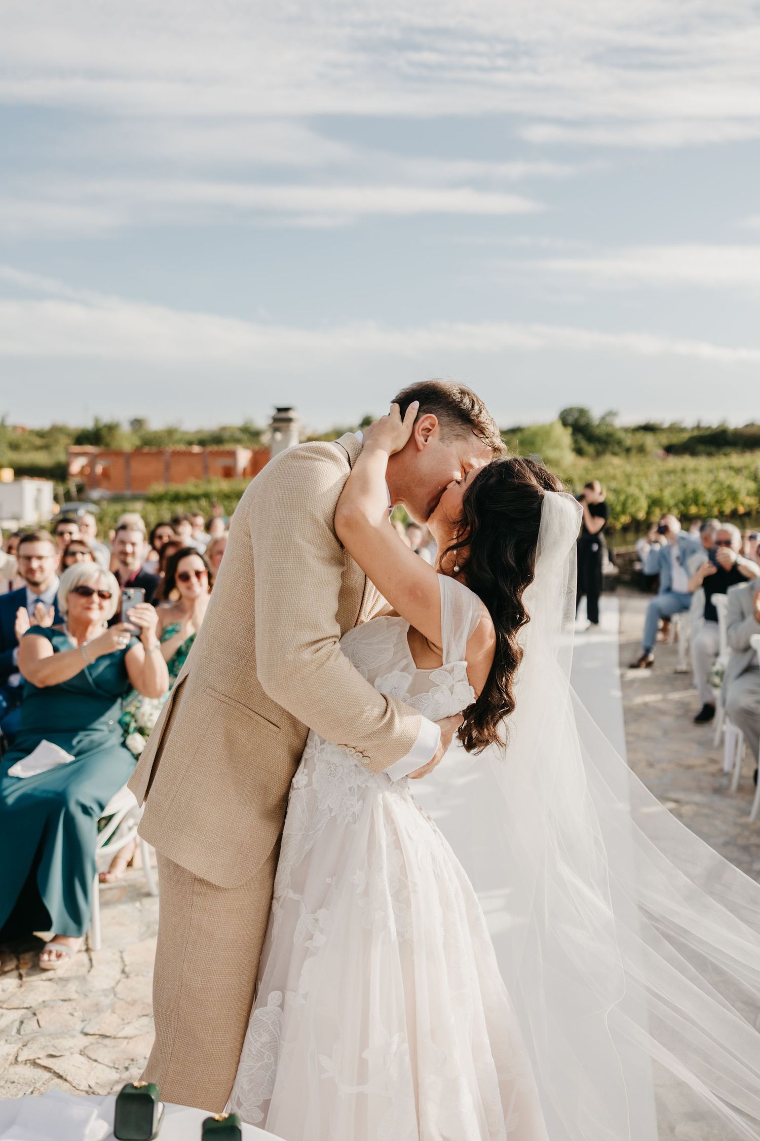 A couple shares their first kiss as newlyweds at an outdoor stone patio wedding venue in Italy.