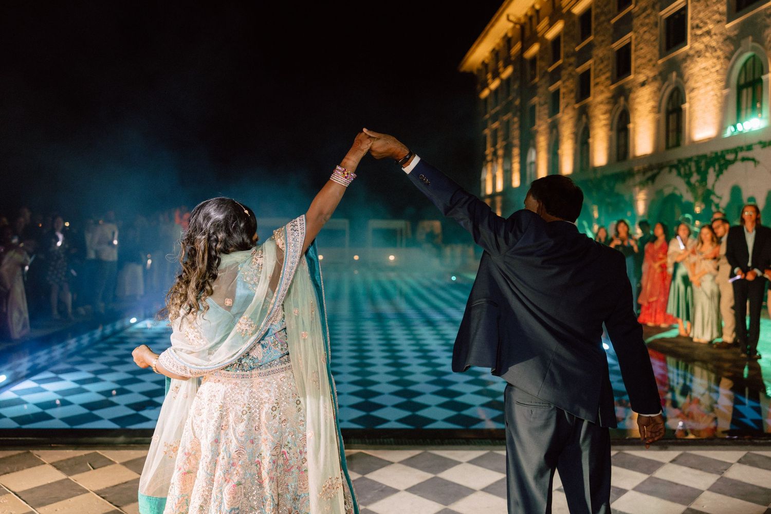 Bride and groom dancing on checkered floor at elegant outdoor night wedding reception venue.