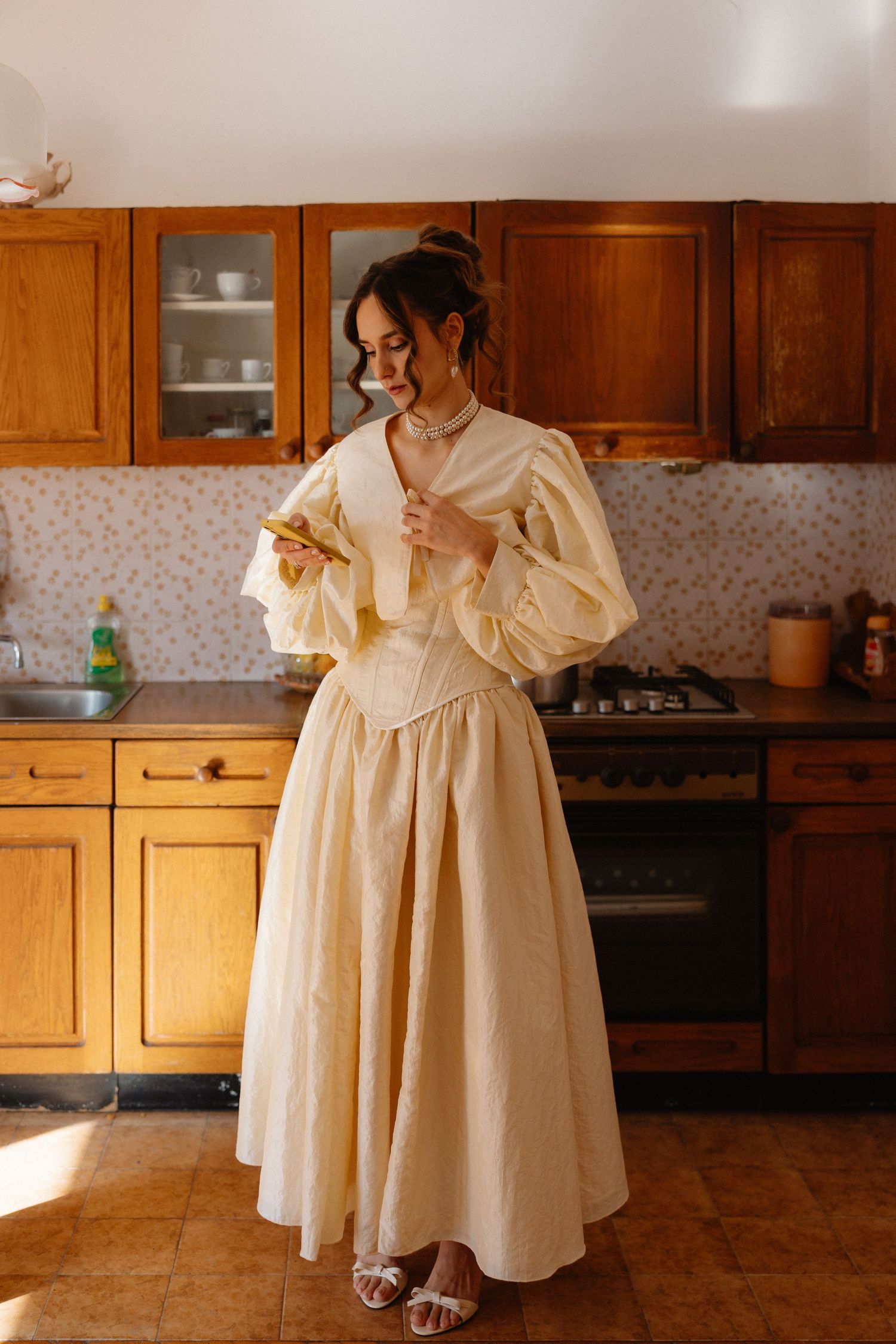 Elegant cream-colored dress with puffy sleeves shown in a kitchen setting.