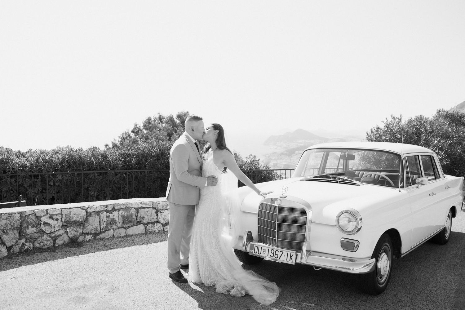 Vintage white Mercedes-Benz automobile parked against mountainous backdrop.