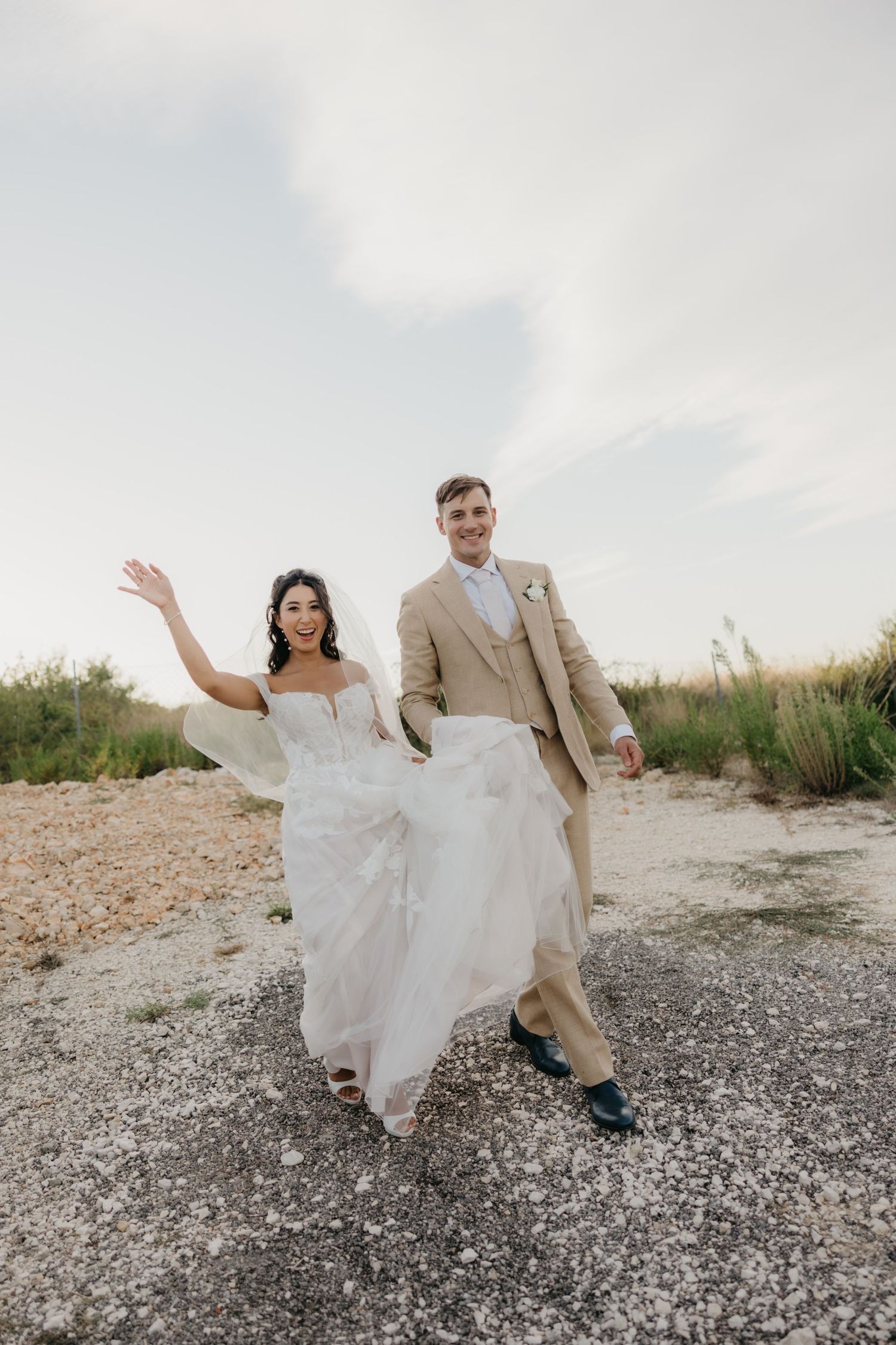 Couple dances playfully on gravel path surrounded by natural landscape.