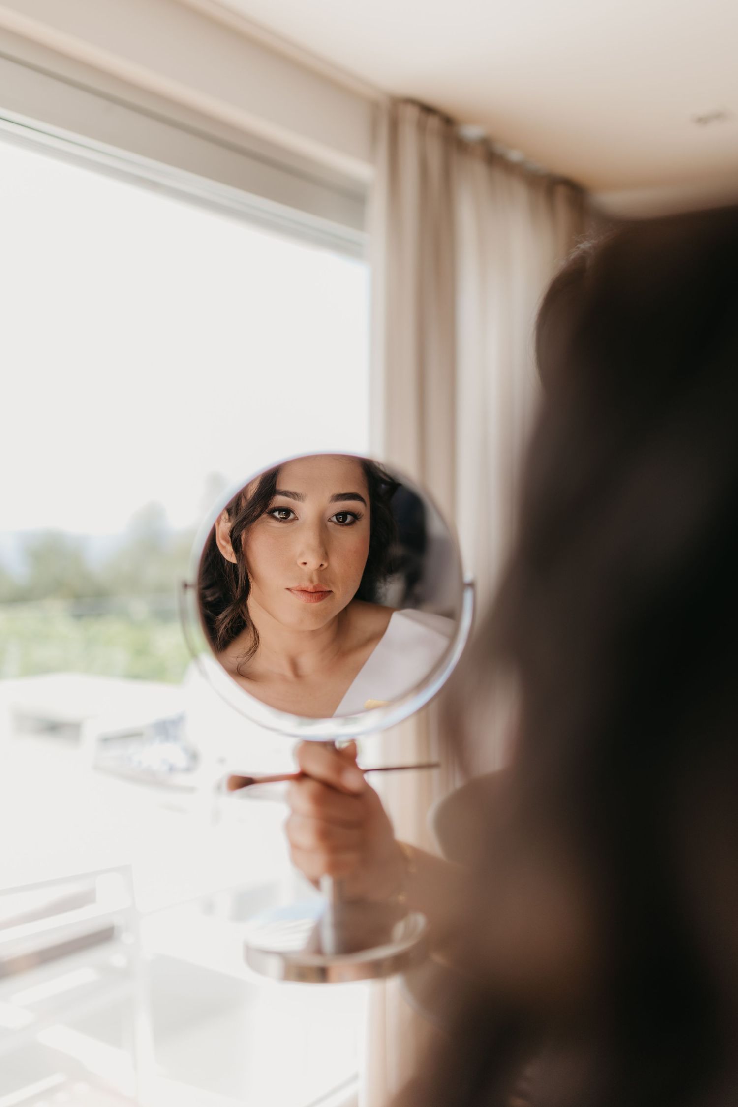 Reflection in handheld mirror during bridal makeup preparation.