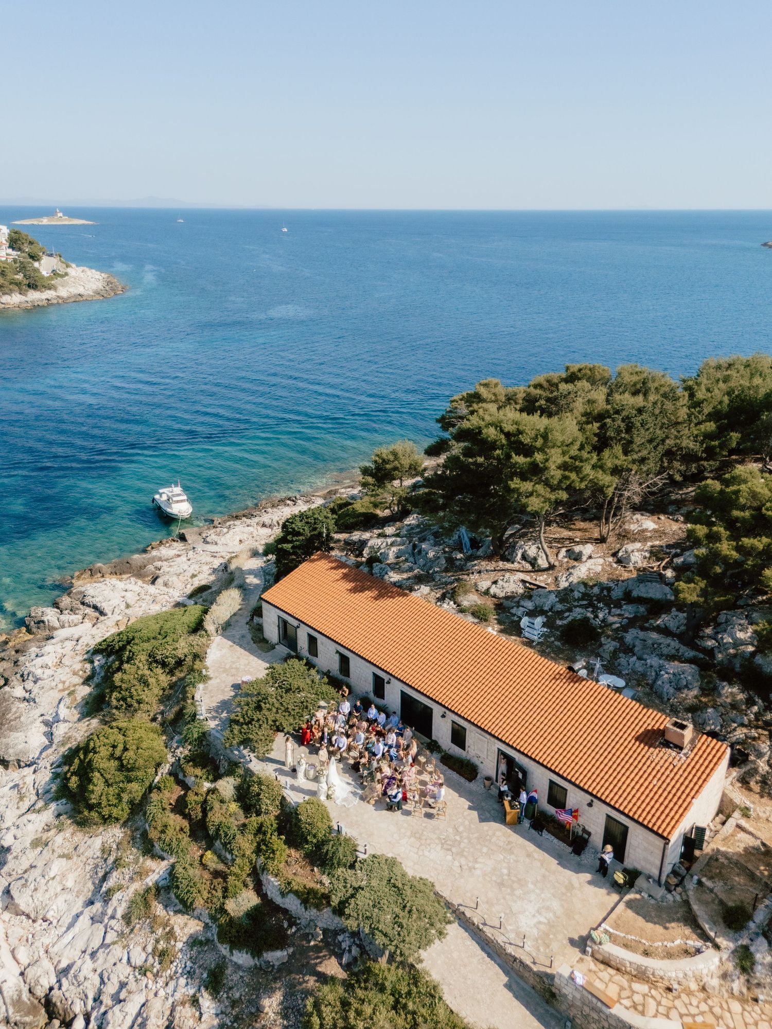 Aerial view of coastal wedding venue with red roof surrounded by turquoise Adriatic Sea.