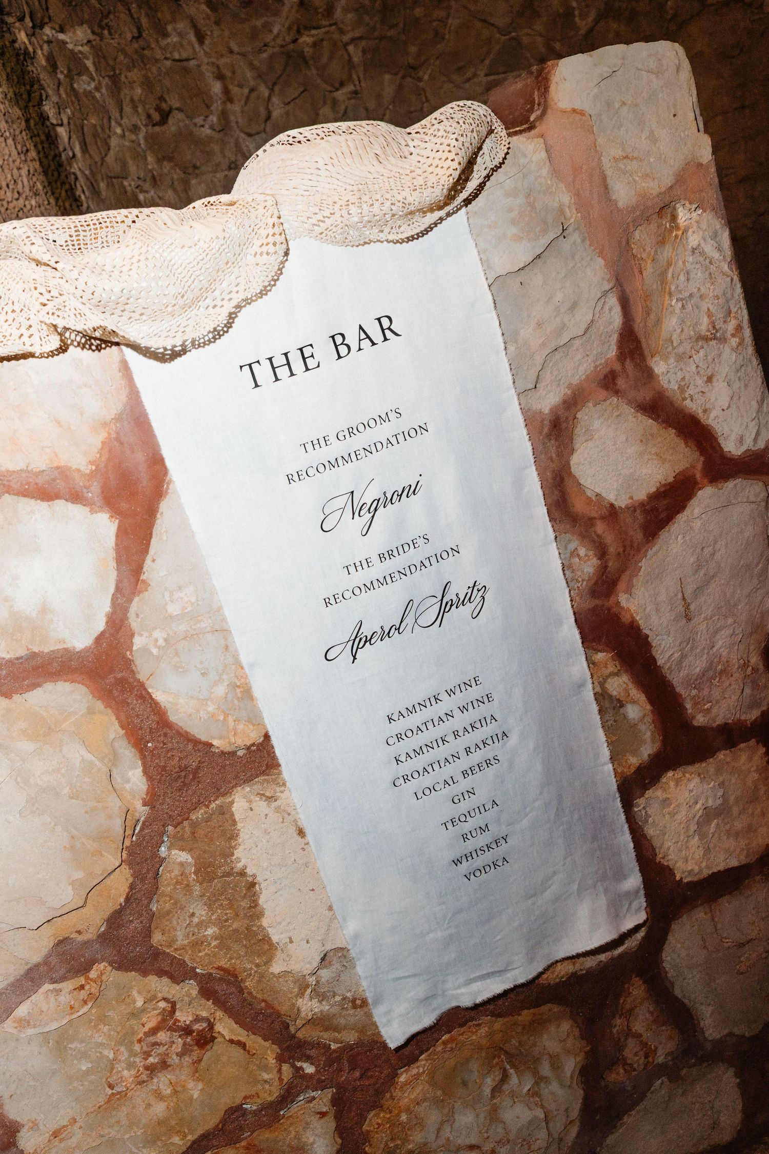 Elegant wedding bar menu on linen fabric displaying Negroni and Aperol Spritz recommendations.
