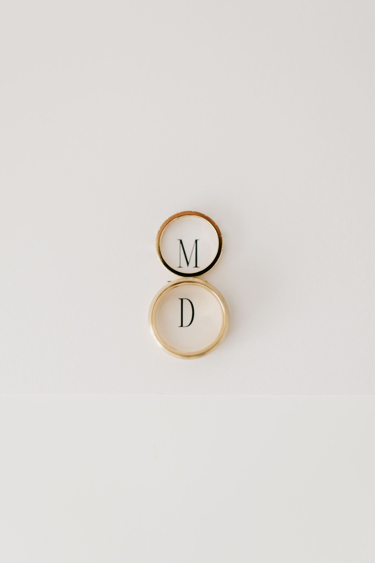 Two gold wedding rings with initials M and D on white background.