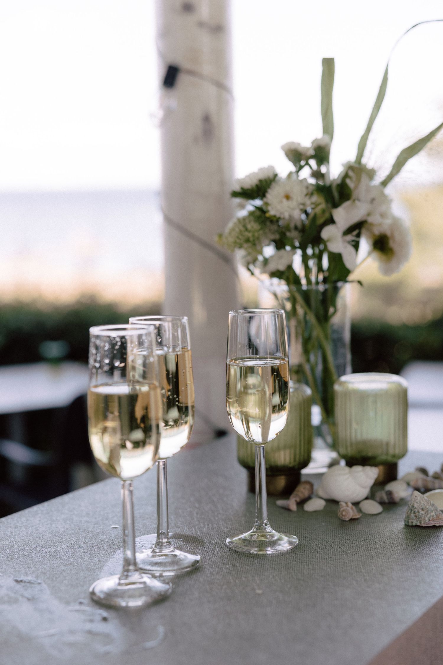 Champagne flutes and white floral centerpiece on an elegant wedding reception table.