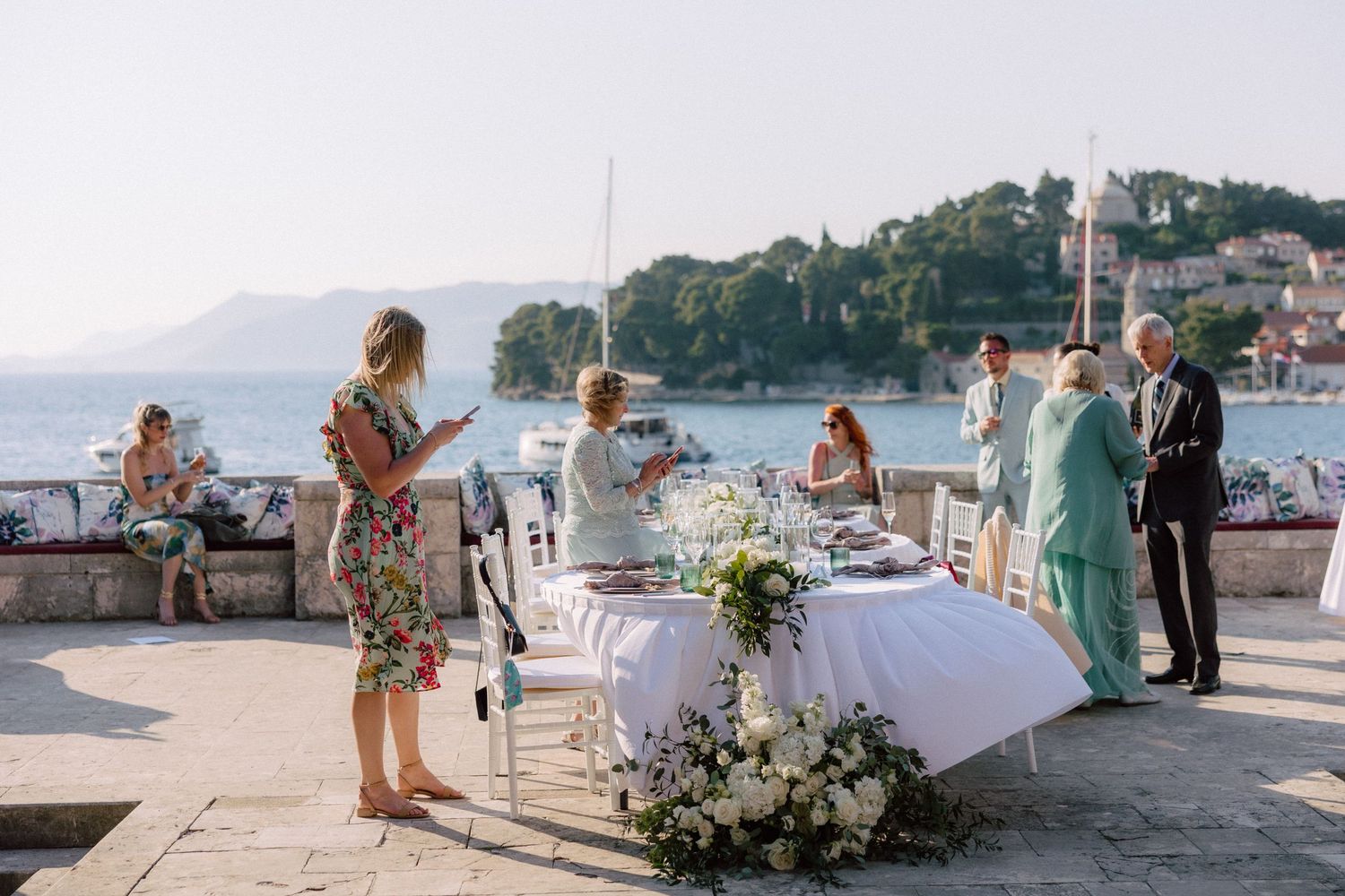 Scenic coastal wedding venue with mountains and boats in the background.