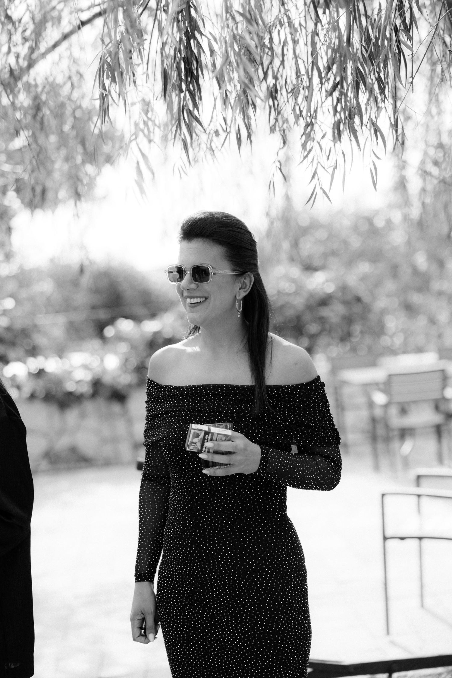 Black and white outdoor portrait showing laughter under willow trees.