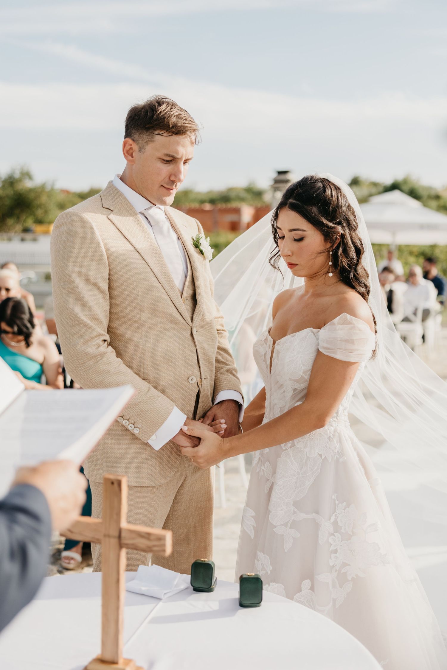 A couple in tan and white attire shares tender moments during their outdoor wedding ceremony.
