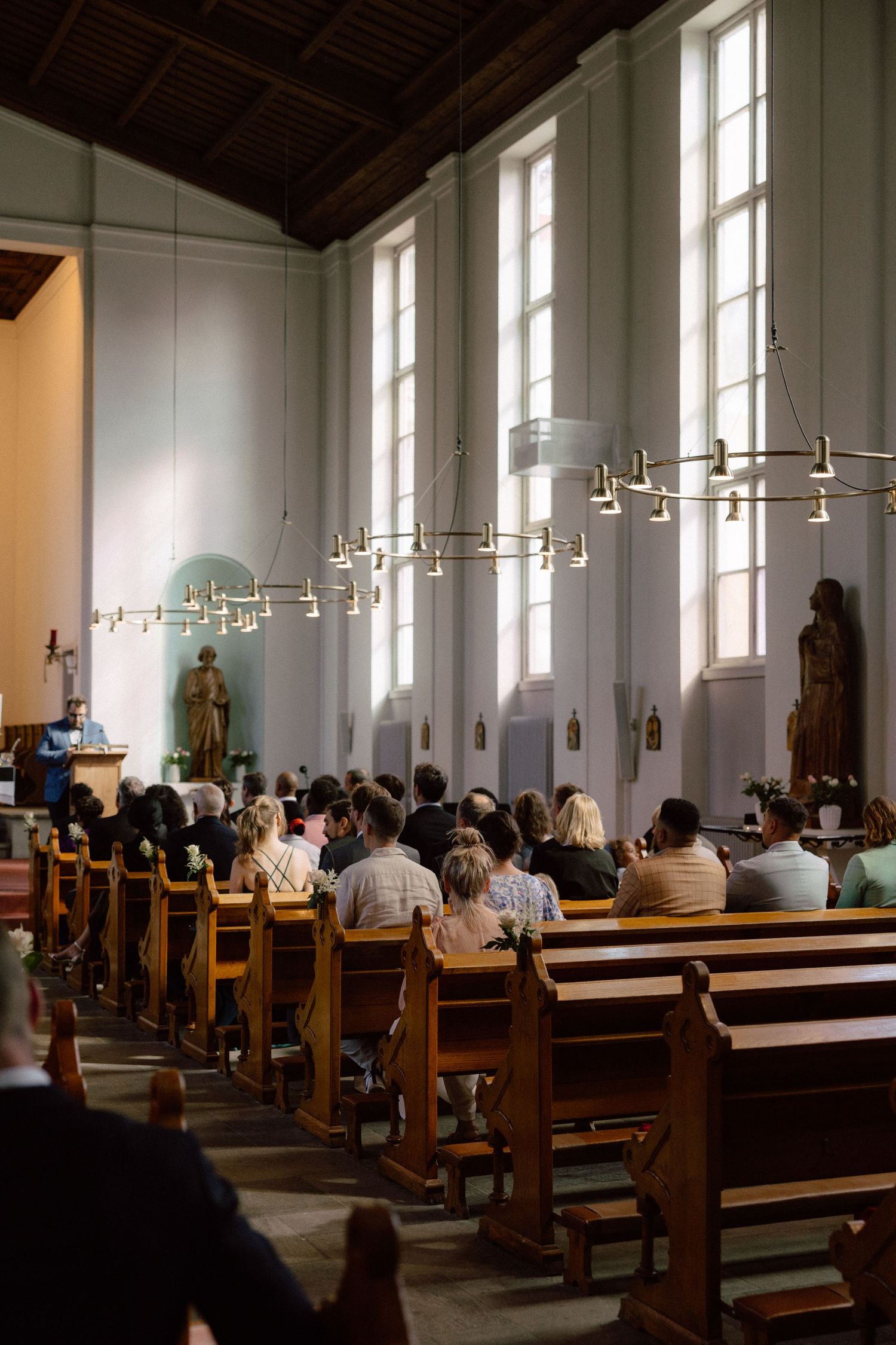 Sunlight streams through windows into church sanctuary filled with wedding attendees.