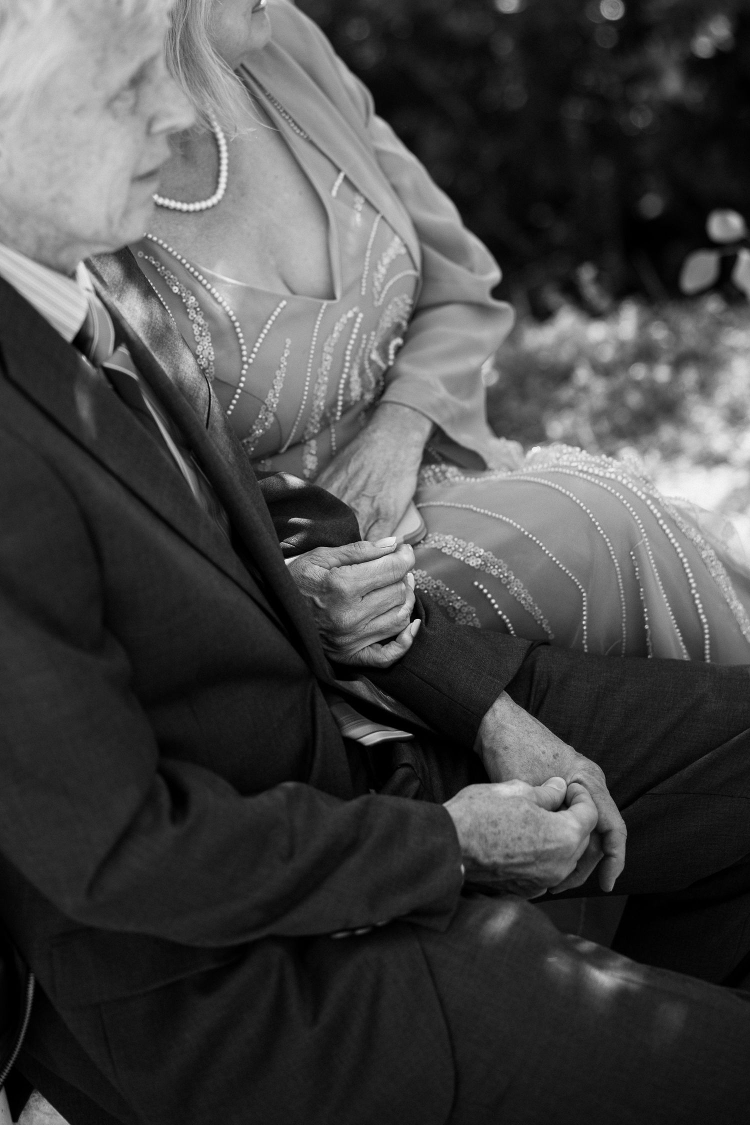 Black and white detail shot of hands holding a program or paper during wedding ceremony.