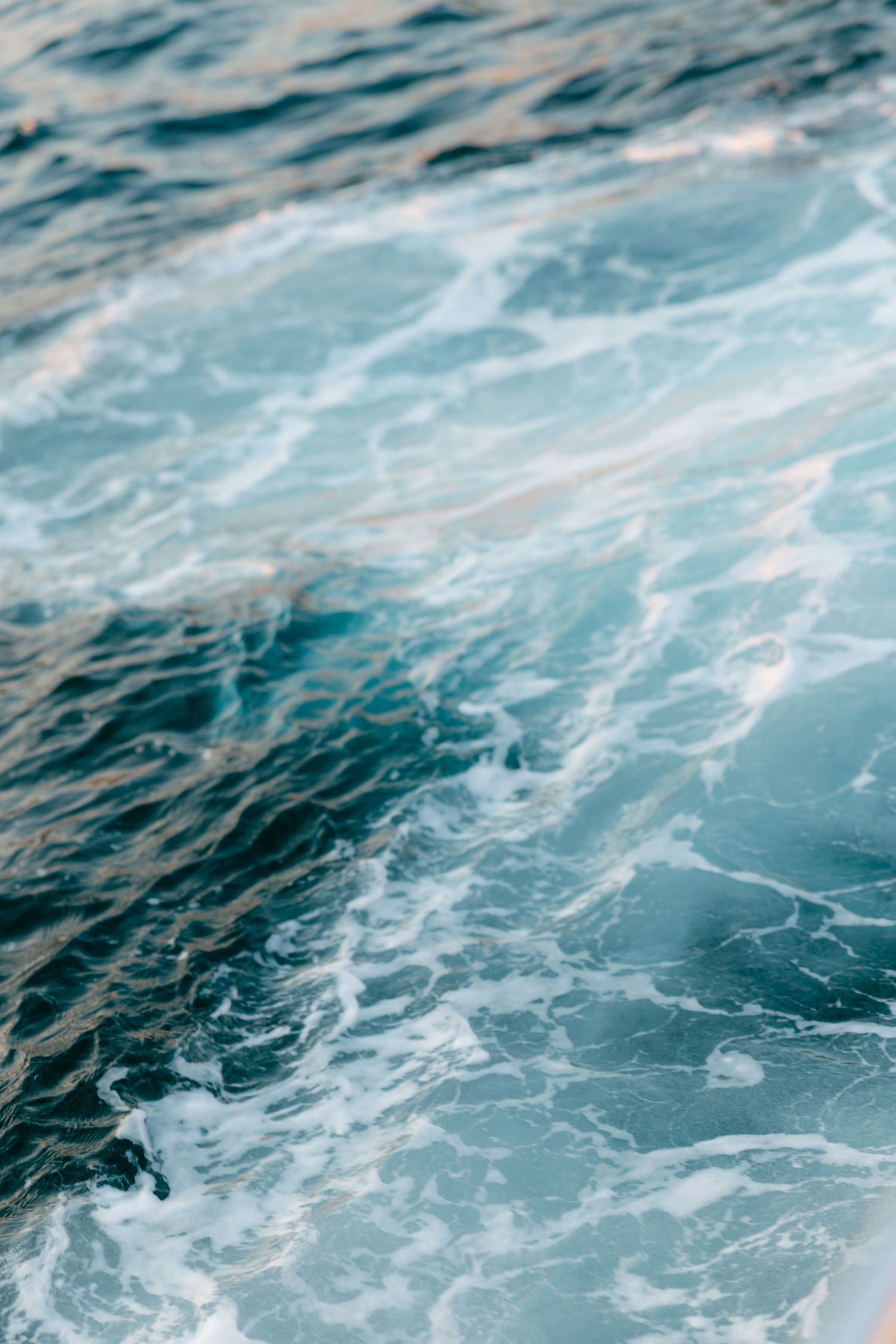 Turquoise ocean waves creating a swirling pattern in clear Mediterranean waters.