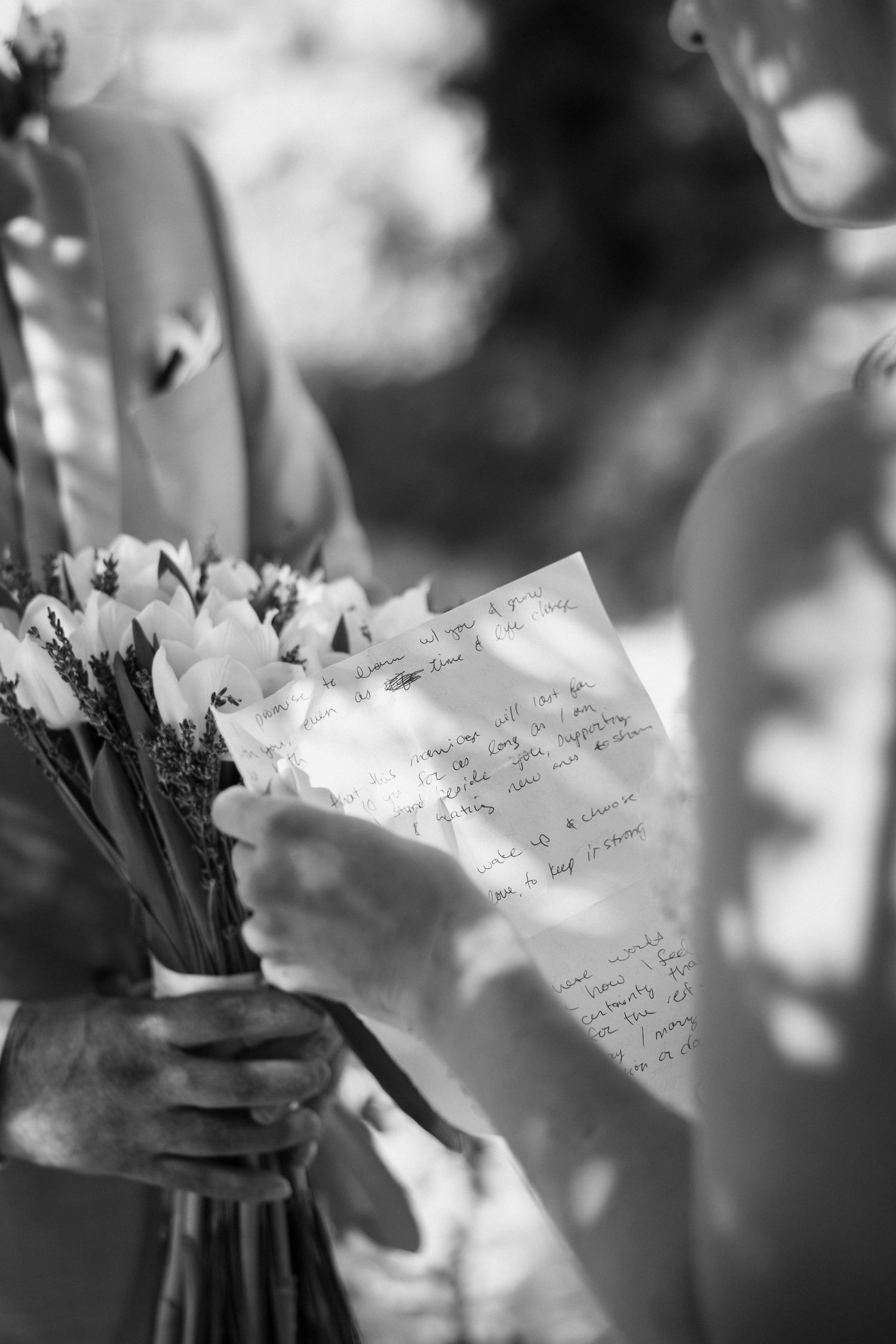 Black and white close-up of wedding ceremony programs and bouquet being held.