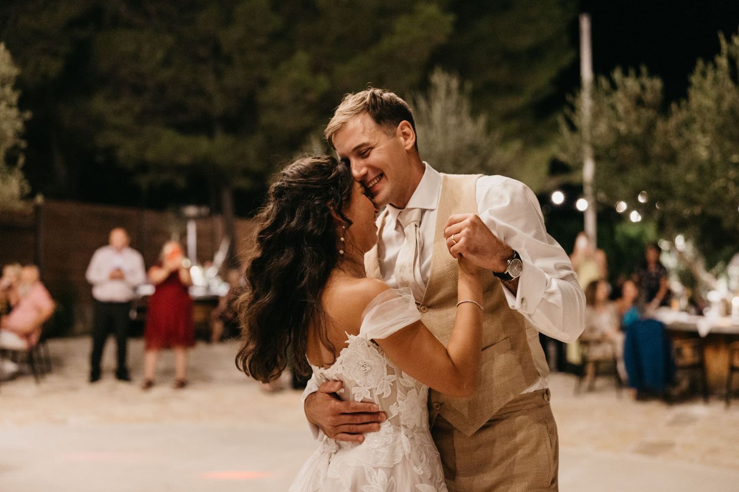 Evening wedding celebration with dancing under outdoor lights.