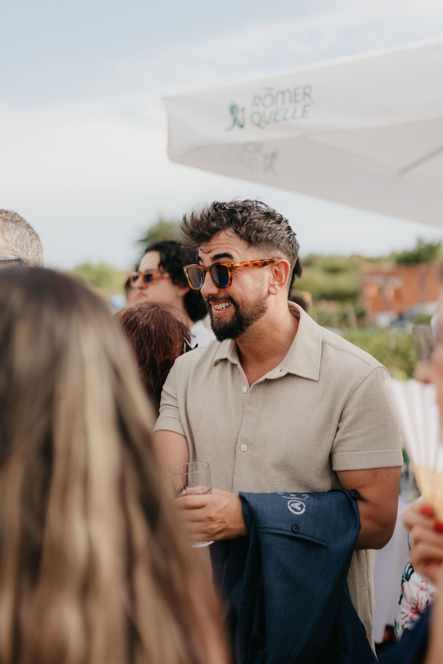 People socializing and laughing at an outdoor wine event in Italy.