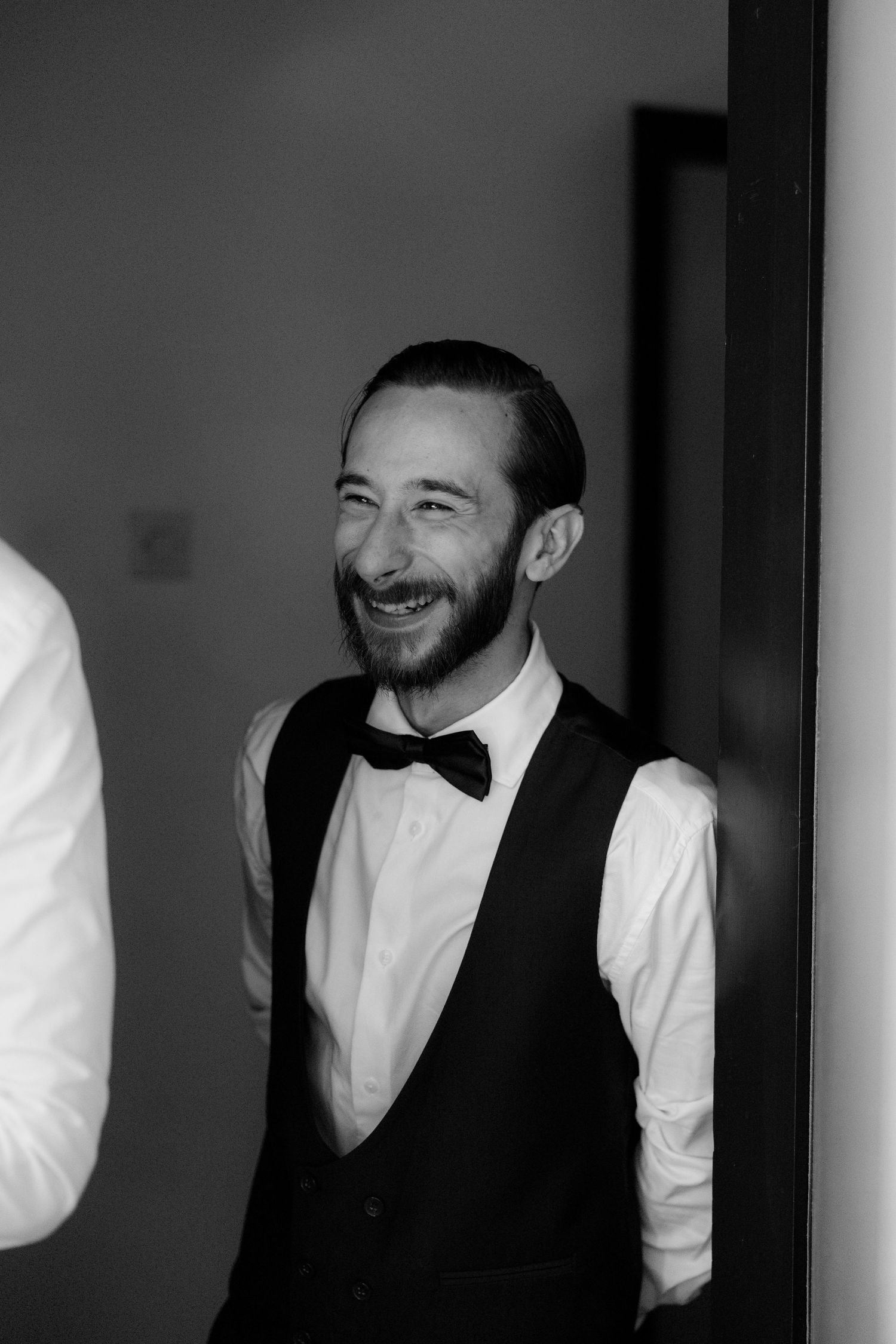 A black and white portrait series showing someone in a white shirt and vest smiling in different poses.