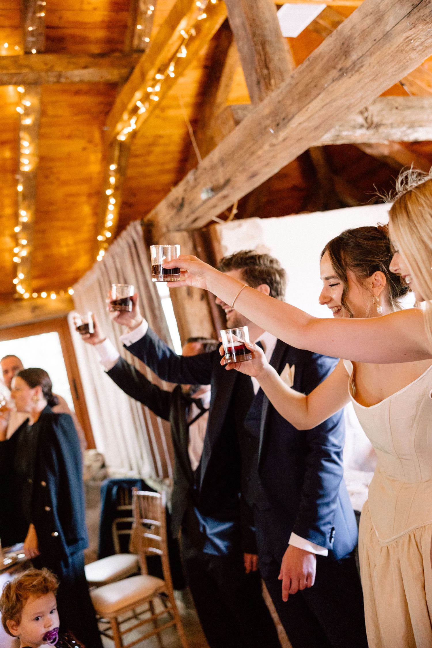 Wedding celebration in a rustic wooden barn venue decorated with string lights.