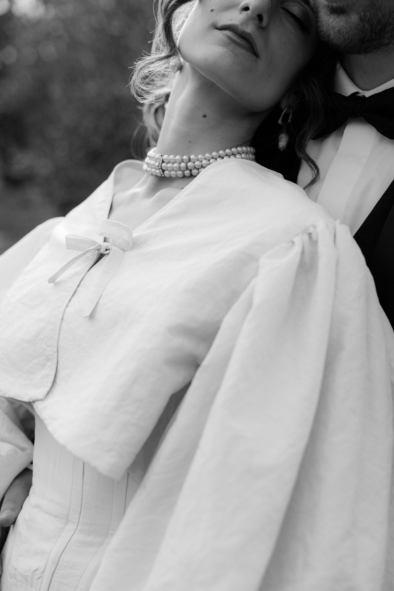 Black and white close-up shots of a pearl necklace and vintage-style wedding dress with dramatic collar details.