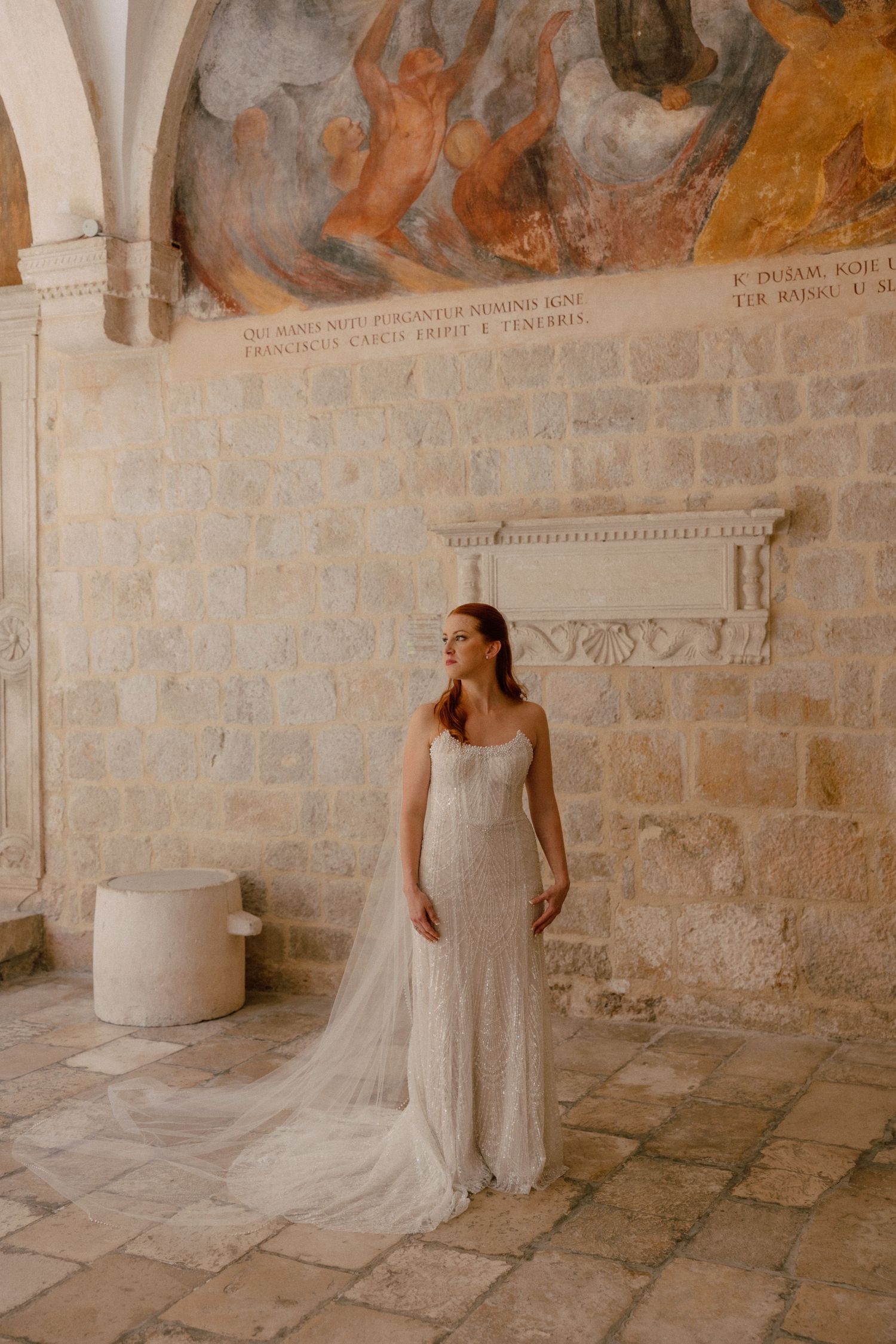 Wedding photographs in a rustic stone hallway with elegant murals adorning the walls in Dubrovnik, Croatia.
