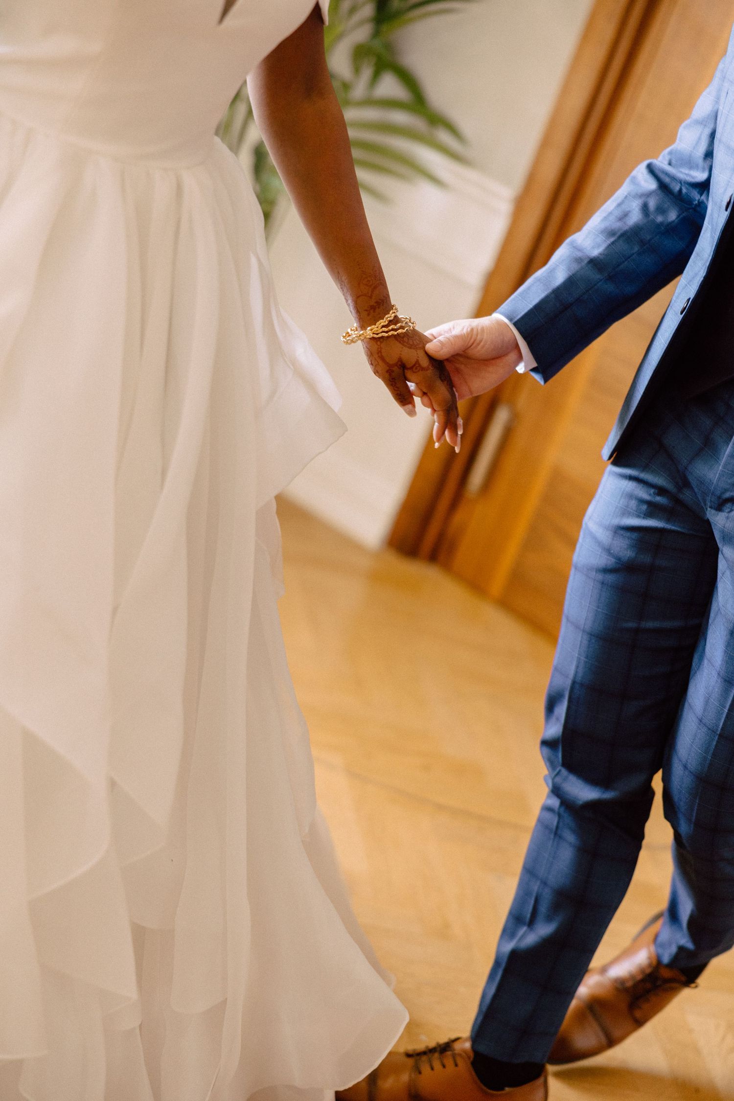 Bride in white gown and groom in blue suit holding hands at wedding ceremony.