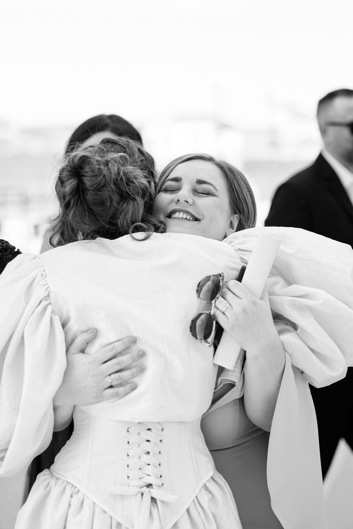 A group sharing warm embraces in white dresses during a special celebration.
