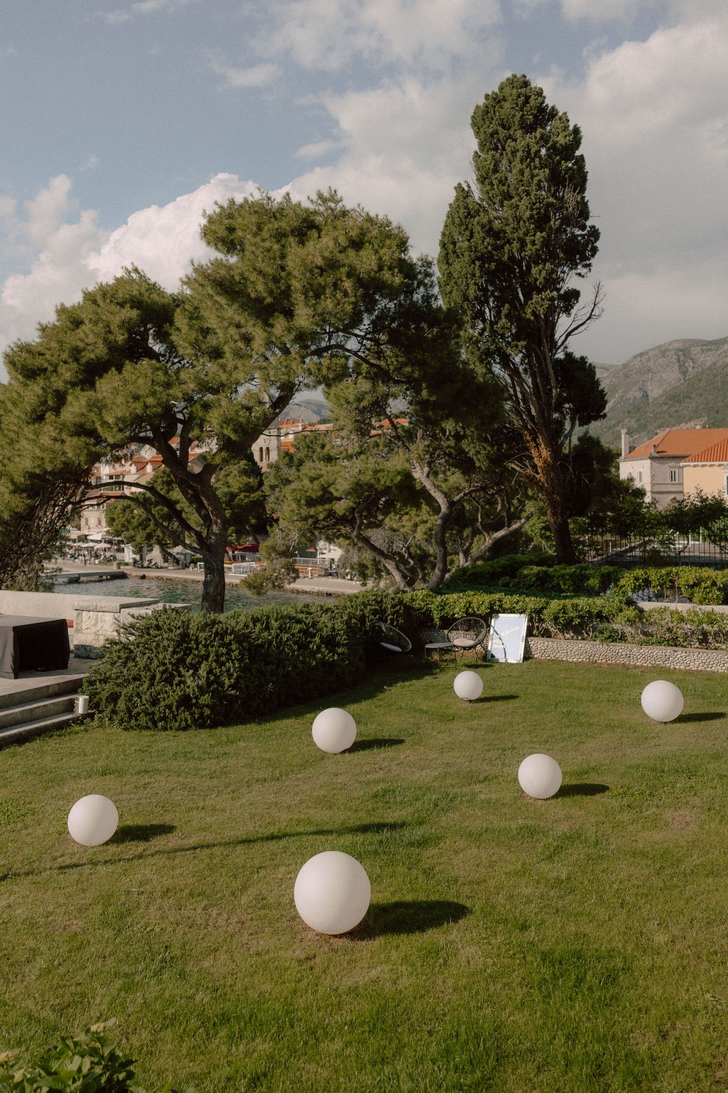 Large white decorative spheres scattered across a manicured lawn with trees and mountains in background.