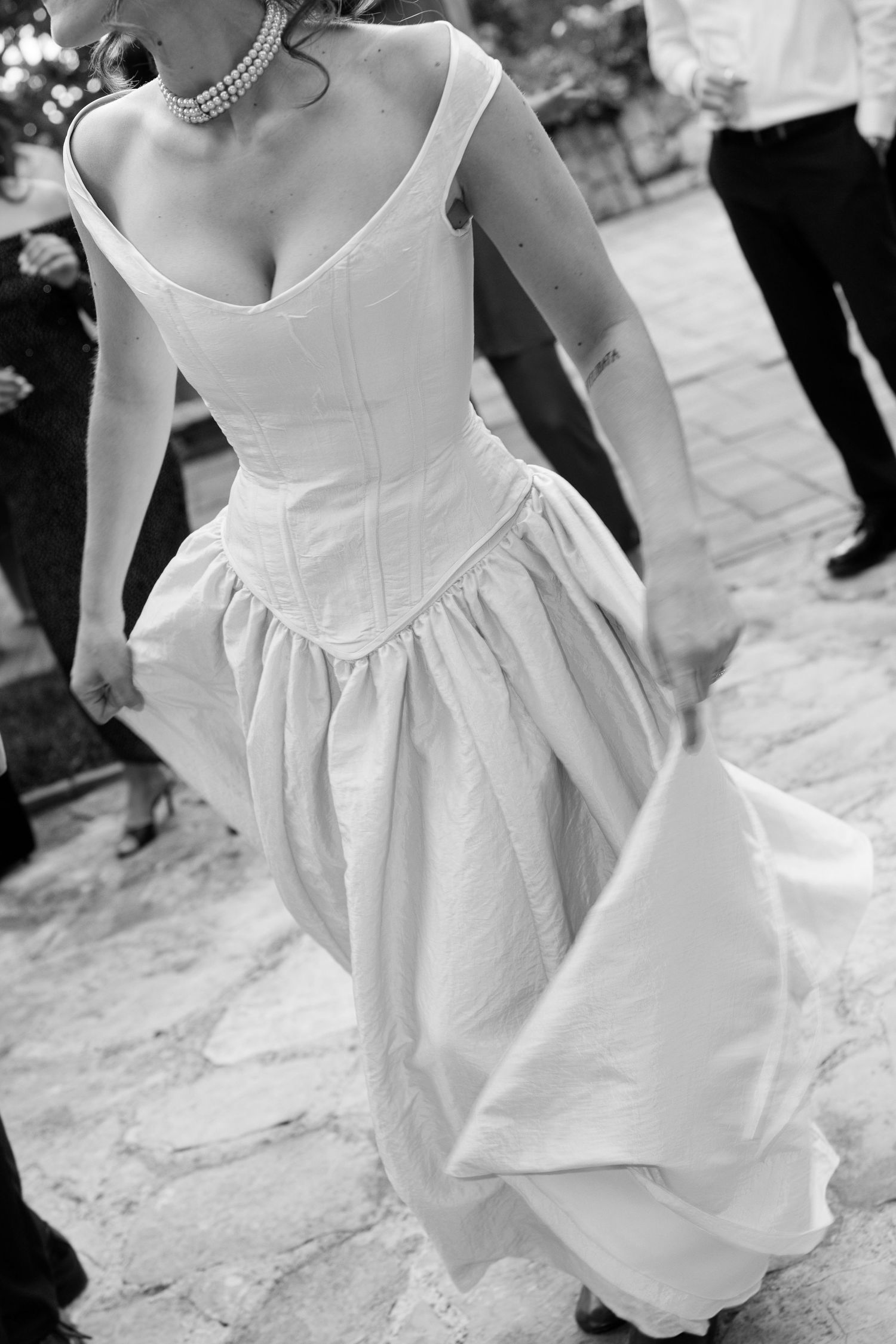 Detail shot of a white wedding dress with pleated skirt and fitted bodice.