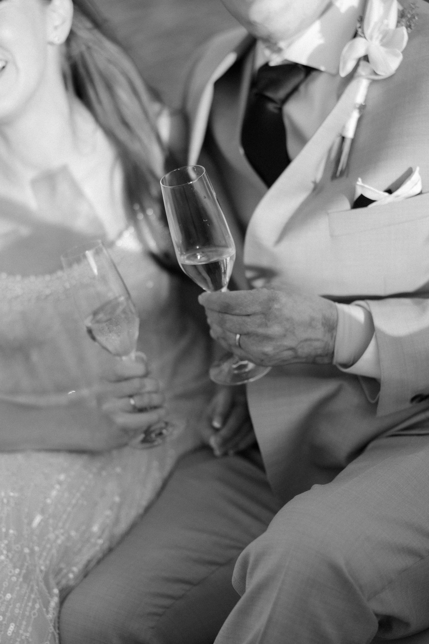 Wedding reception guests in formal attire holding wine glasses at a seaside venue.