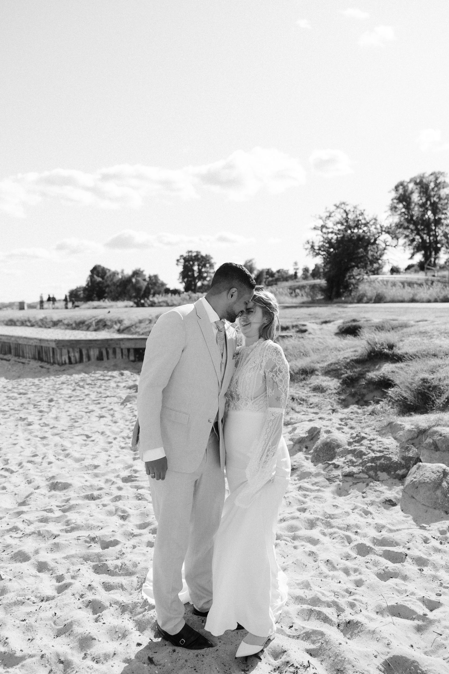 A romantic wedding couple shares an intimate moment on a sandy beach.