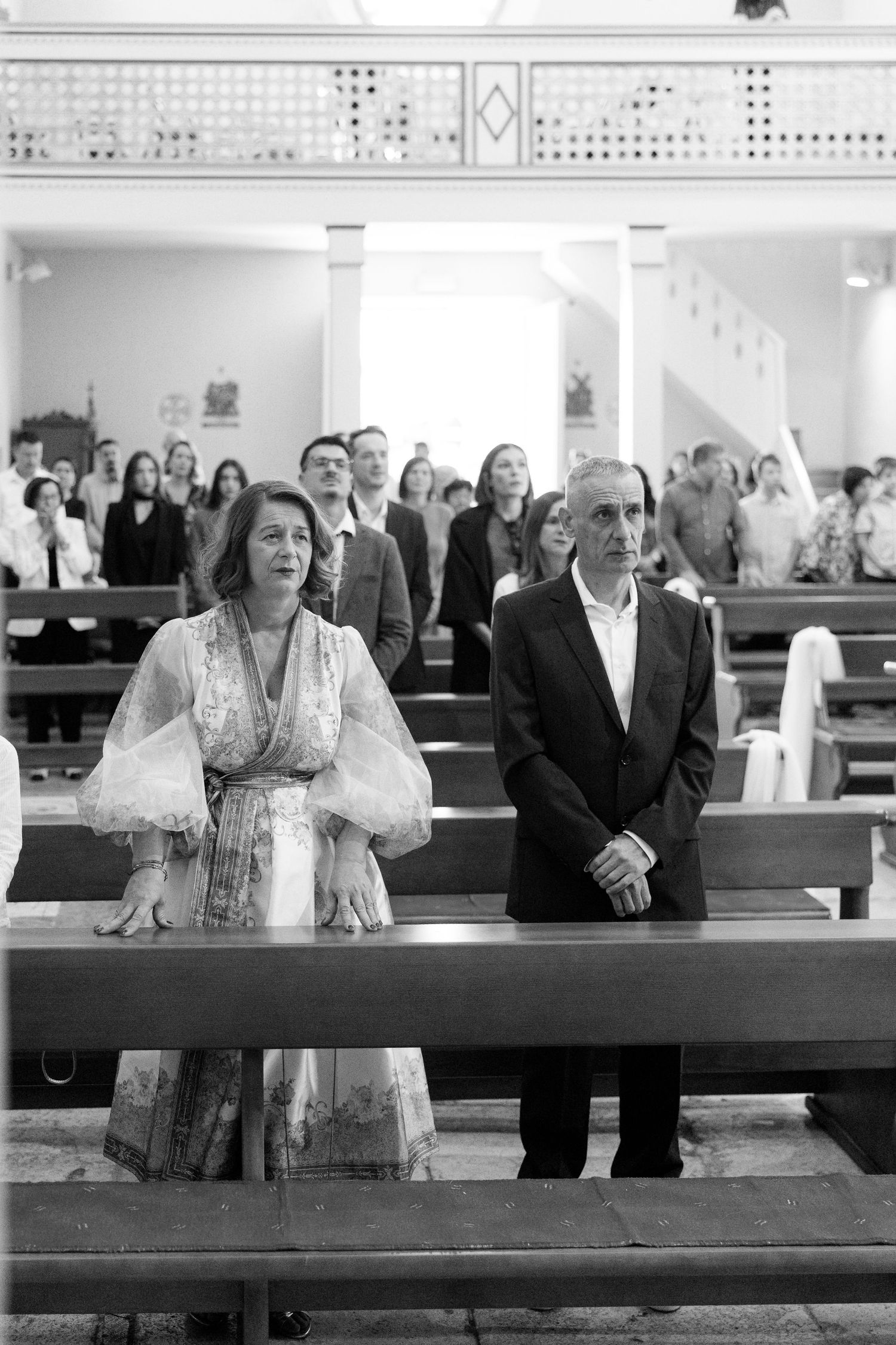 Wedding guests seated in church pews during a ceremony in black and white photography.