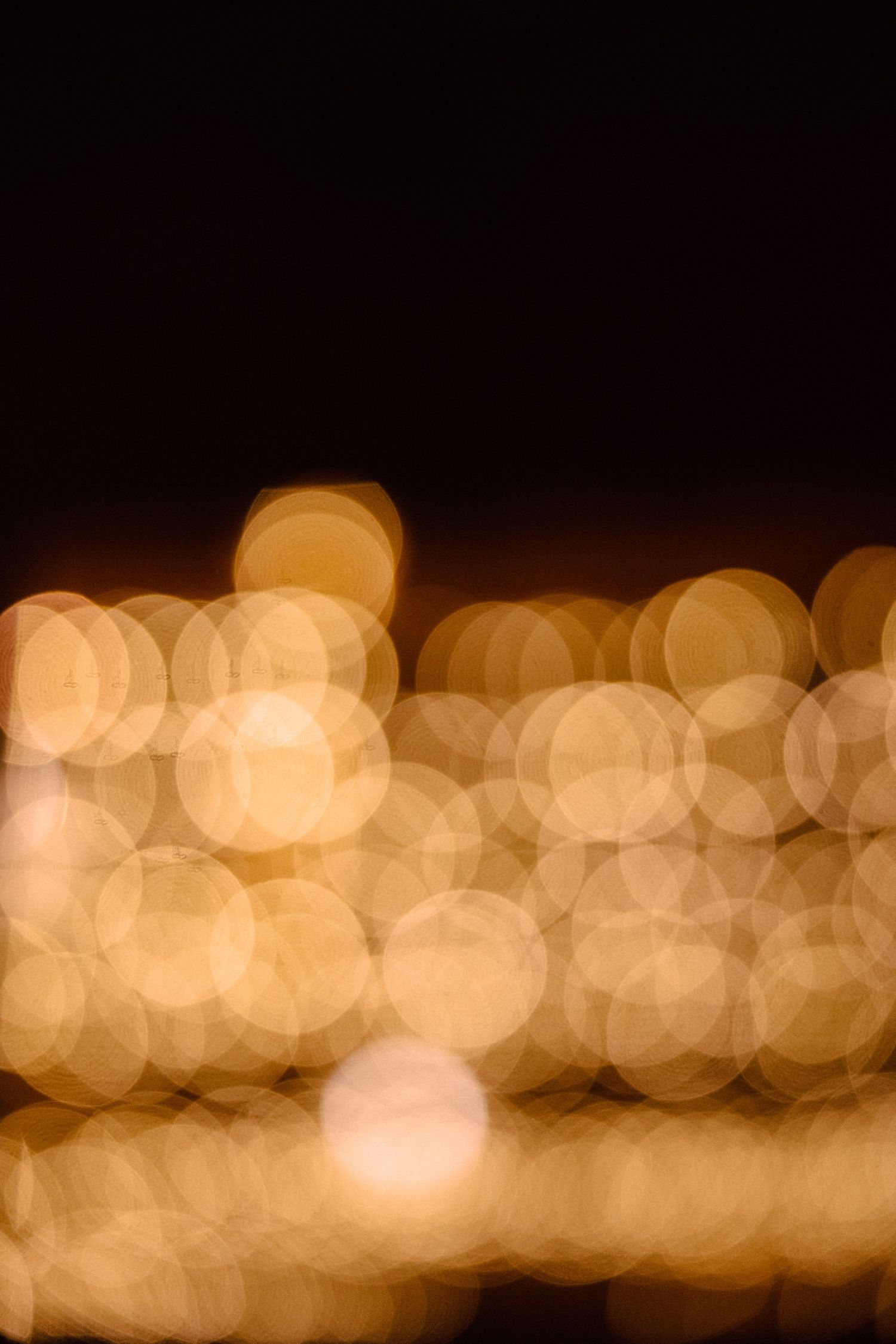 Abstract golden bokeh lights creating a dreamy background pattern against dark backdrop.