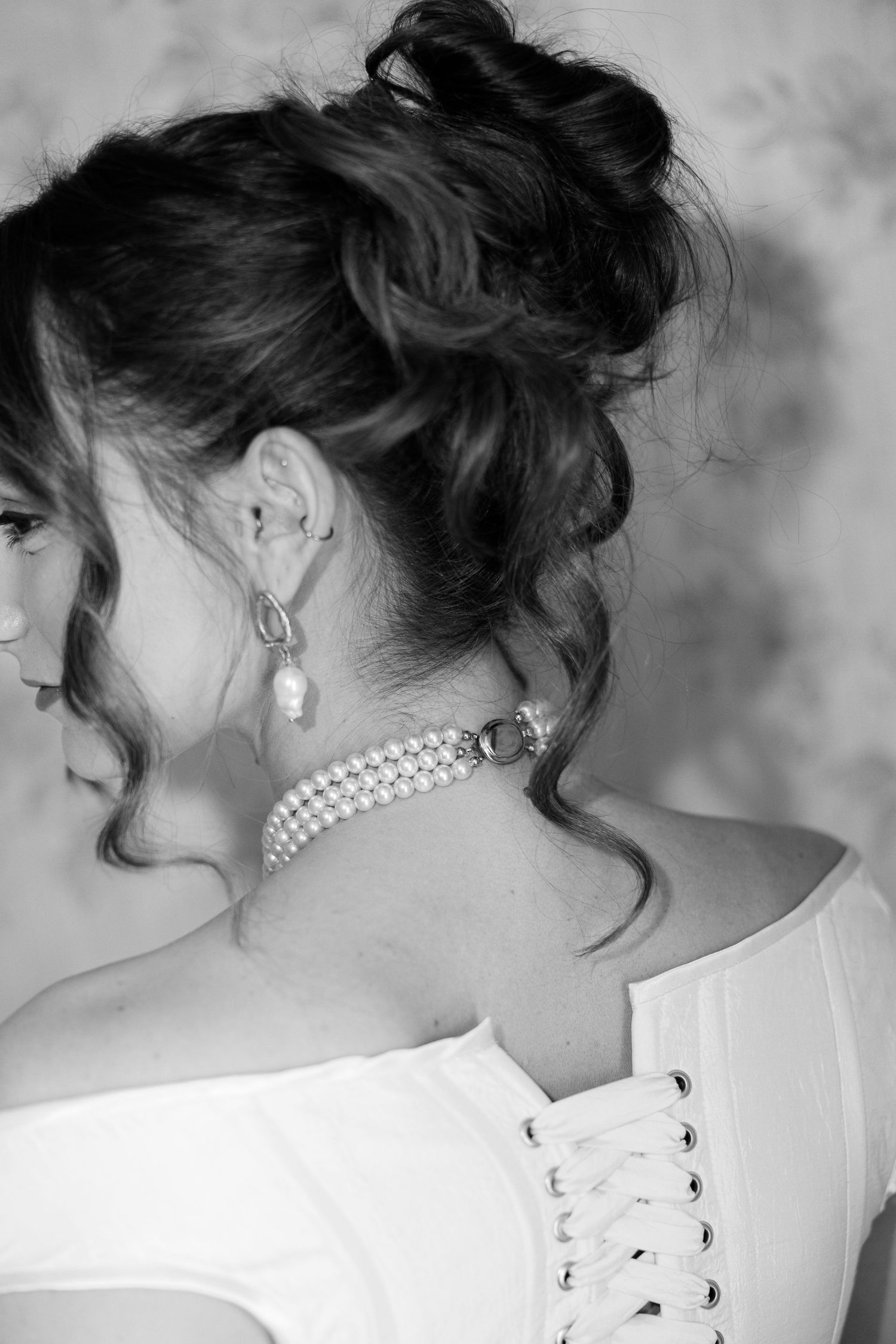 Close-up shots of an elegant updo hairstyle with pearl accessories against a gray background.