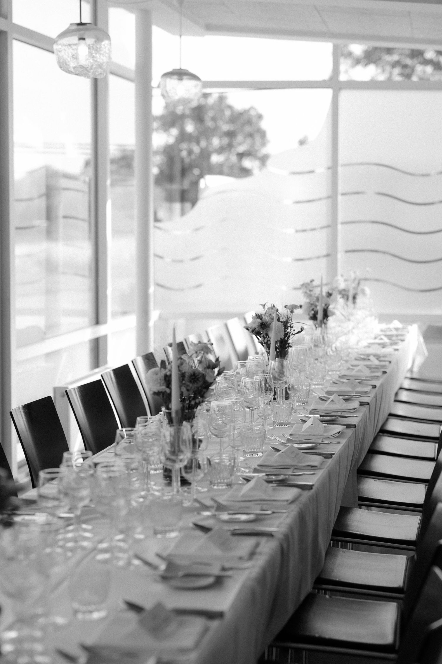 Elegant table setting with floral centerpieces and place settings in a bright modern venue.