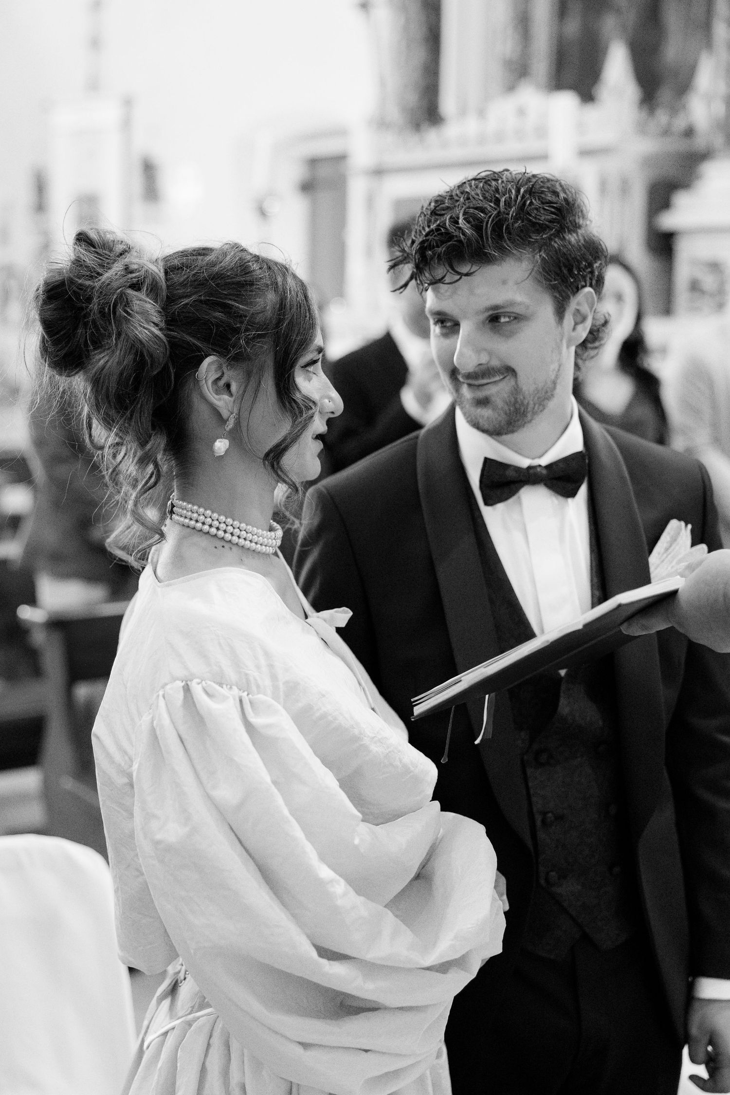A candid black and white wedding moment showing a couple in formal attire looking at a document together.