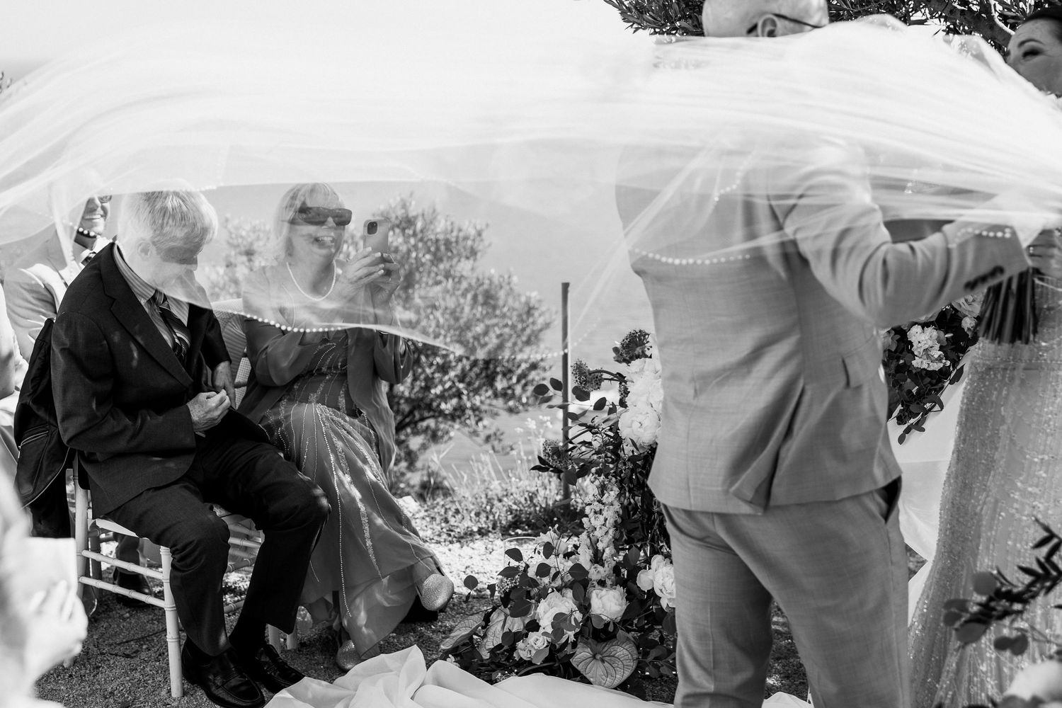 A candid wedding moment captured in black and white against a scenic mountain view.