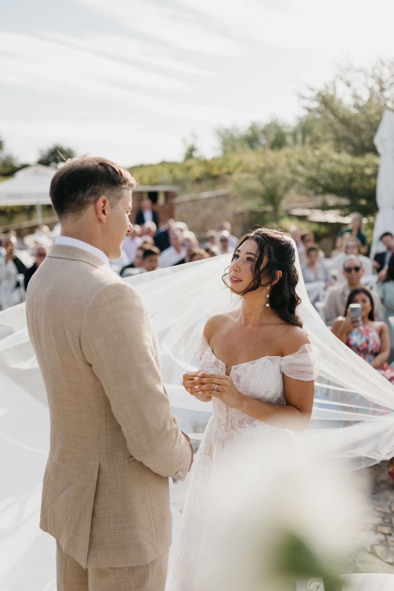 A romantic wedding dance captured outdoors with a flowing white dress and tan suit.
