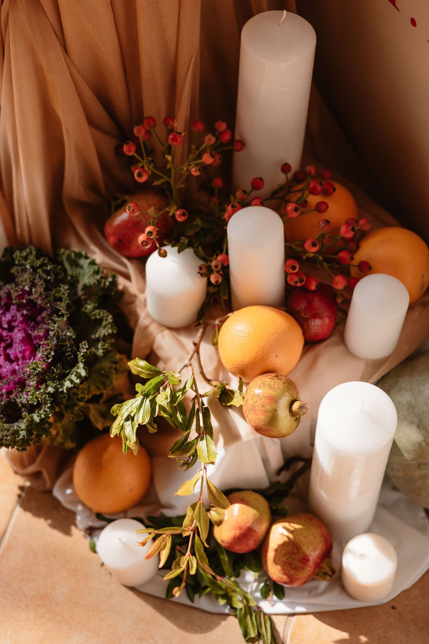Decorative display of white candles, pumpkins, and autumn flowers arranged on a surface.