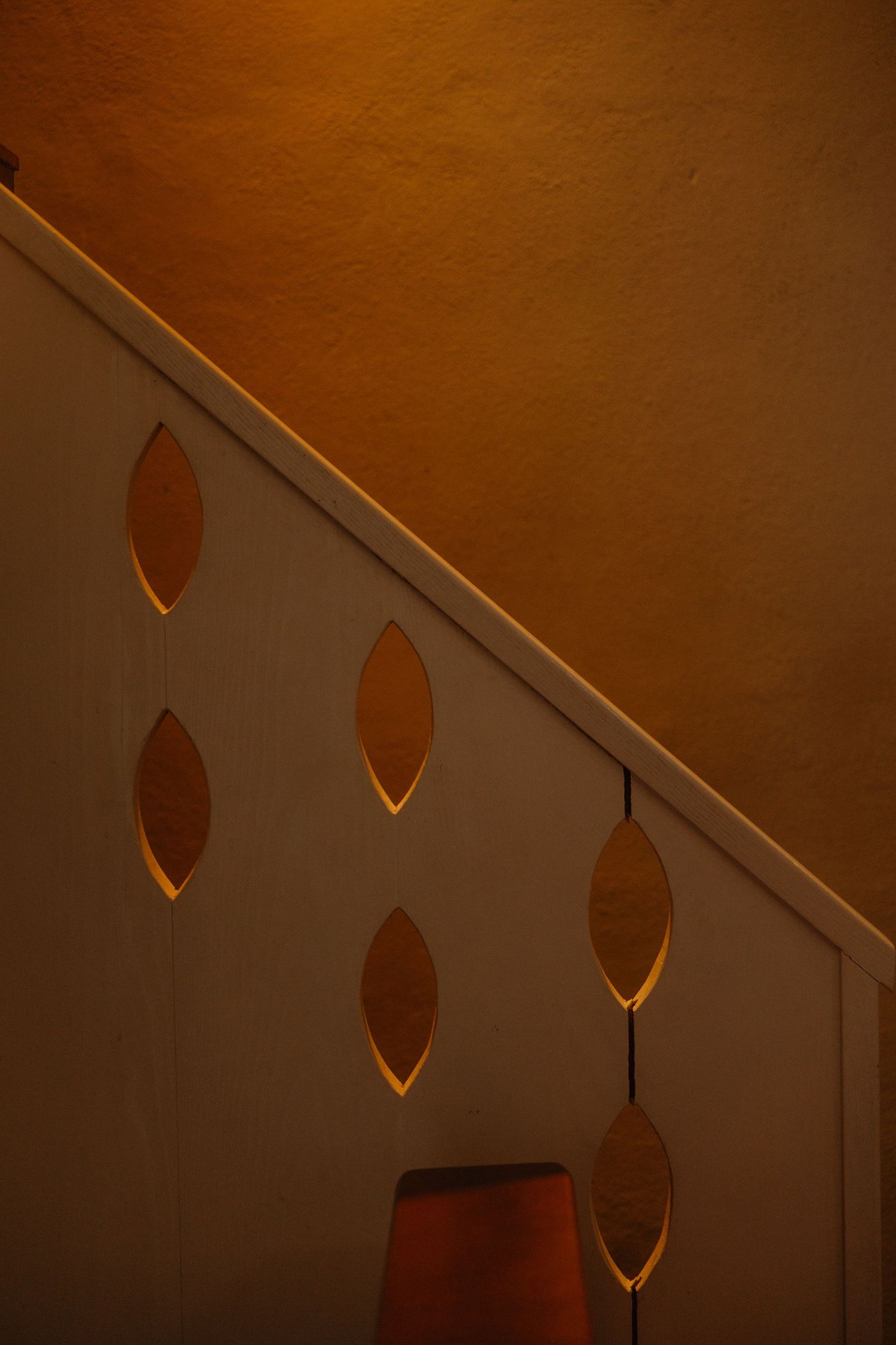 Artistic lighting detail of a warm-toned wall with leaf-shaped shadows.