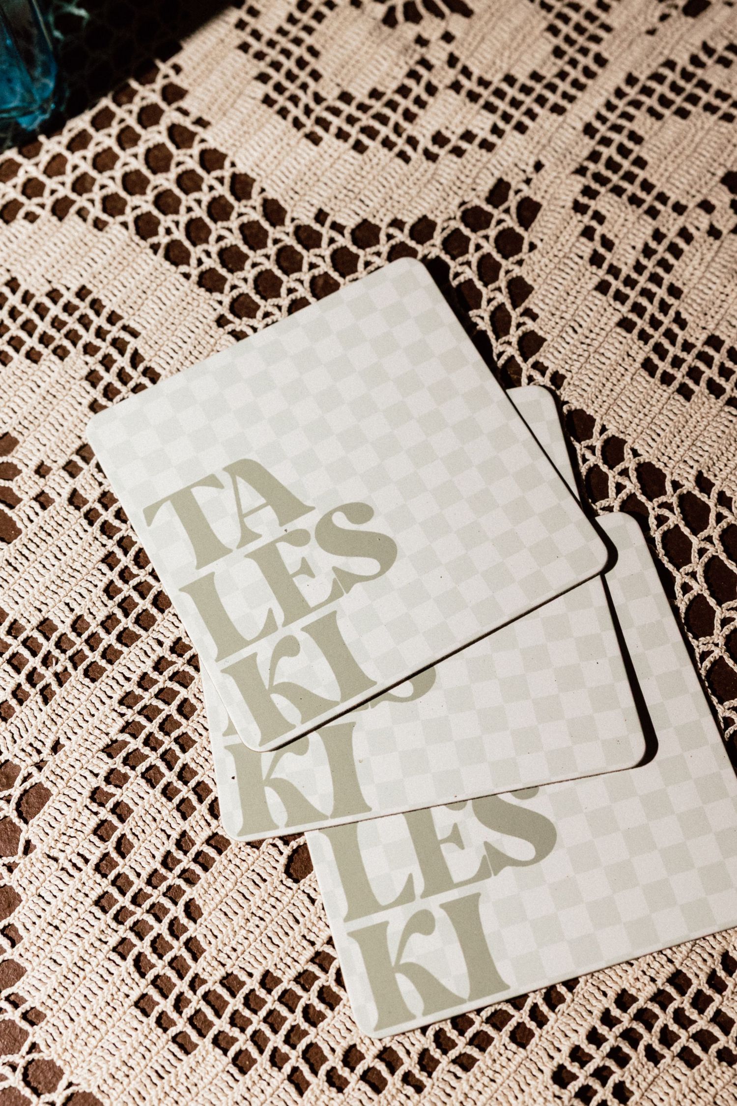 Minimalist wedding stationery with checkered pattern and bold typography reading Tales Kleski on lace tablecloth.